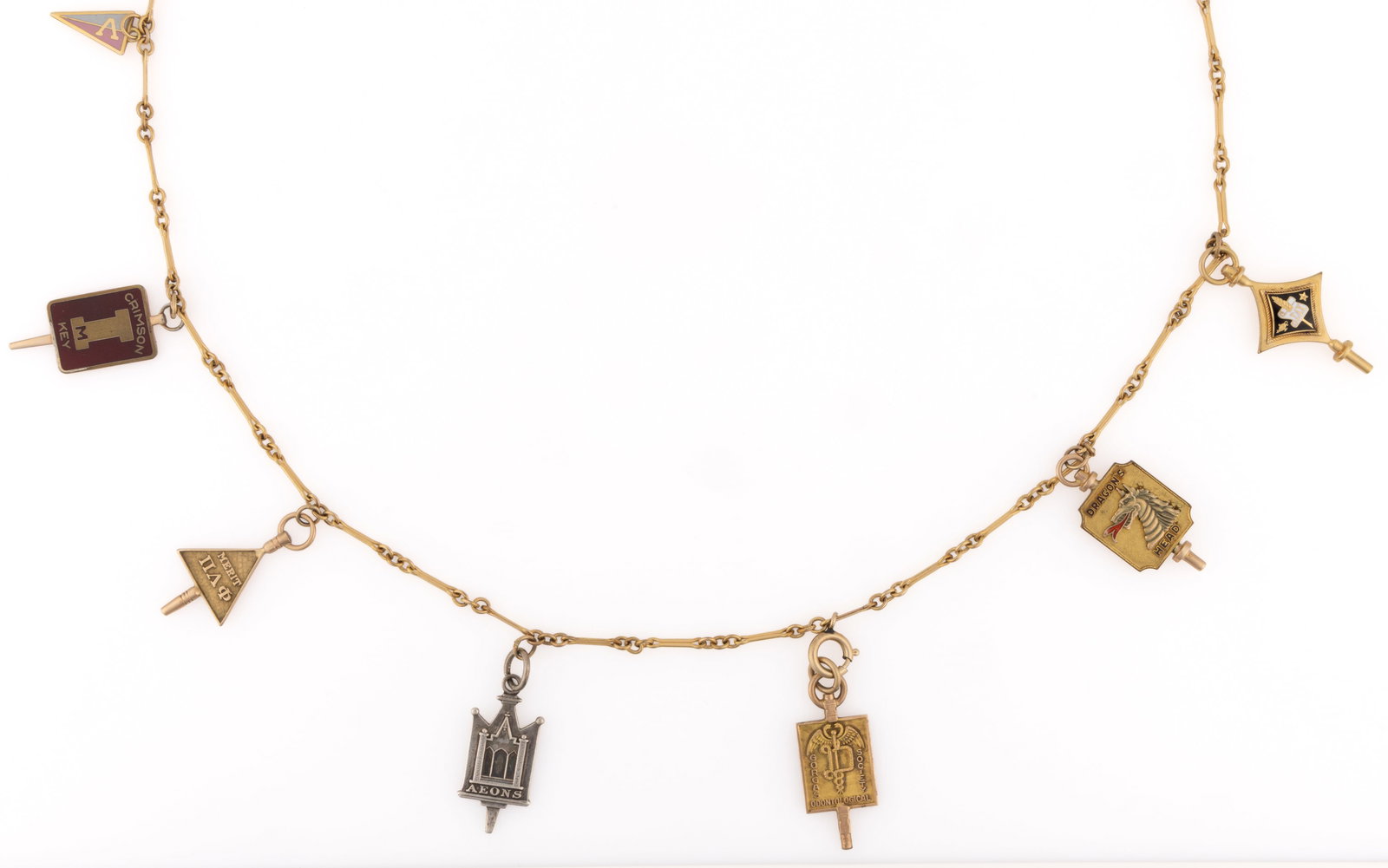 VINTAGE GOLD AND OTHER COLLEGE / SOCIETY CHARMS ON A NECKLACE: VINTAGE GOLD AND OTHER COLLEGE / SOCIETY CHARMS ON A NECKLACE, gold filled bar-link necklace chain with spring ring clasp, featuring seven college / society charms, comprising a marked 10K gold Univer