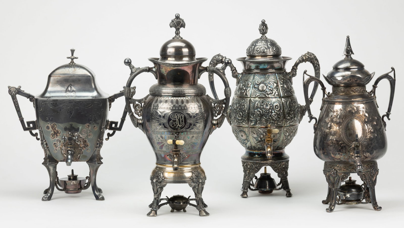 MERIDEN BRITANNIA AND OTHER SILVER-PLATED TEA / HOT WATER URNS, LOT OF FOUR: MERIDEN BRITANNIA AND OTHER SILVER-PLATED TEA / HOT WATER URNS, LOT OF FOUR, each with two handles to sides and a spigot at the bottom of well, topped by a cover, raise on four legs, includes a burner