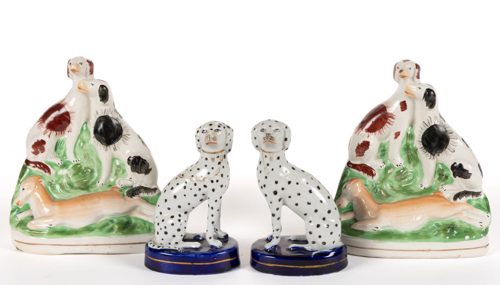 ENGLISH STAFFORDSHIRE HAND-PAINTED CERAMIC DOG PAIRS, LOT OF TWO: ENGLISH STAFFORDSHIRE HAND-PAINTED CERAMIC DOG PAIRS, LOT OF TWO, each on ovoid bases, comprising a sitting dalmatian pair on a cobalt base with gilt collars and chain and a figural group pair depicti