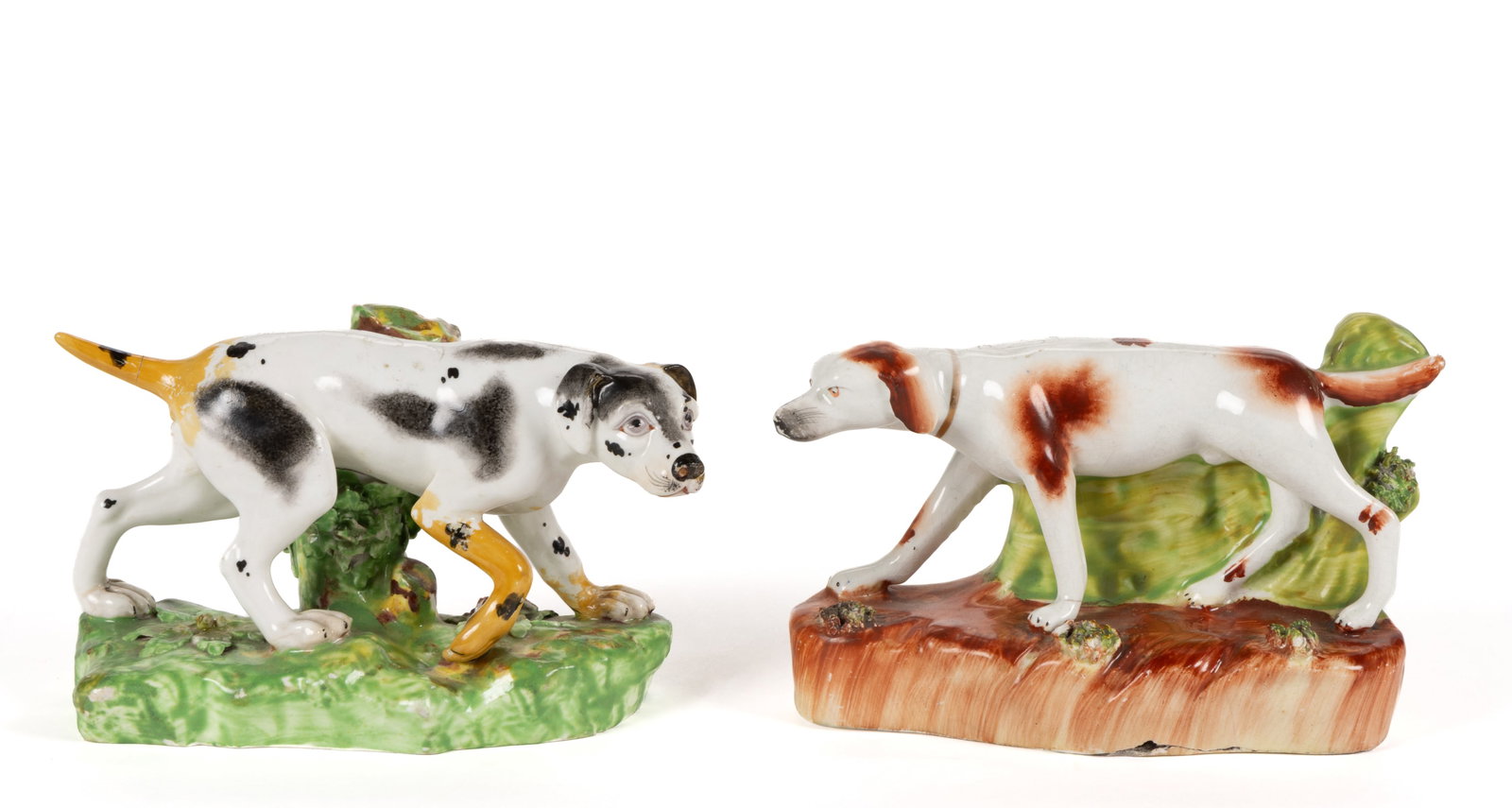 ENGLISH HAND-PAINTED CERAMIC DOGS, LOT OF TWO: ENGLISH HAND-PAINTED CERAMIC DOGS, LOT OF TWO, each standing on a molded base, comprising a Derby porcelain example featuring a black-spotted pointer with tree trunk to back and a Staffordshire red-sp