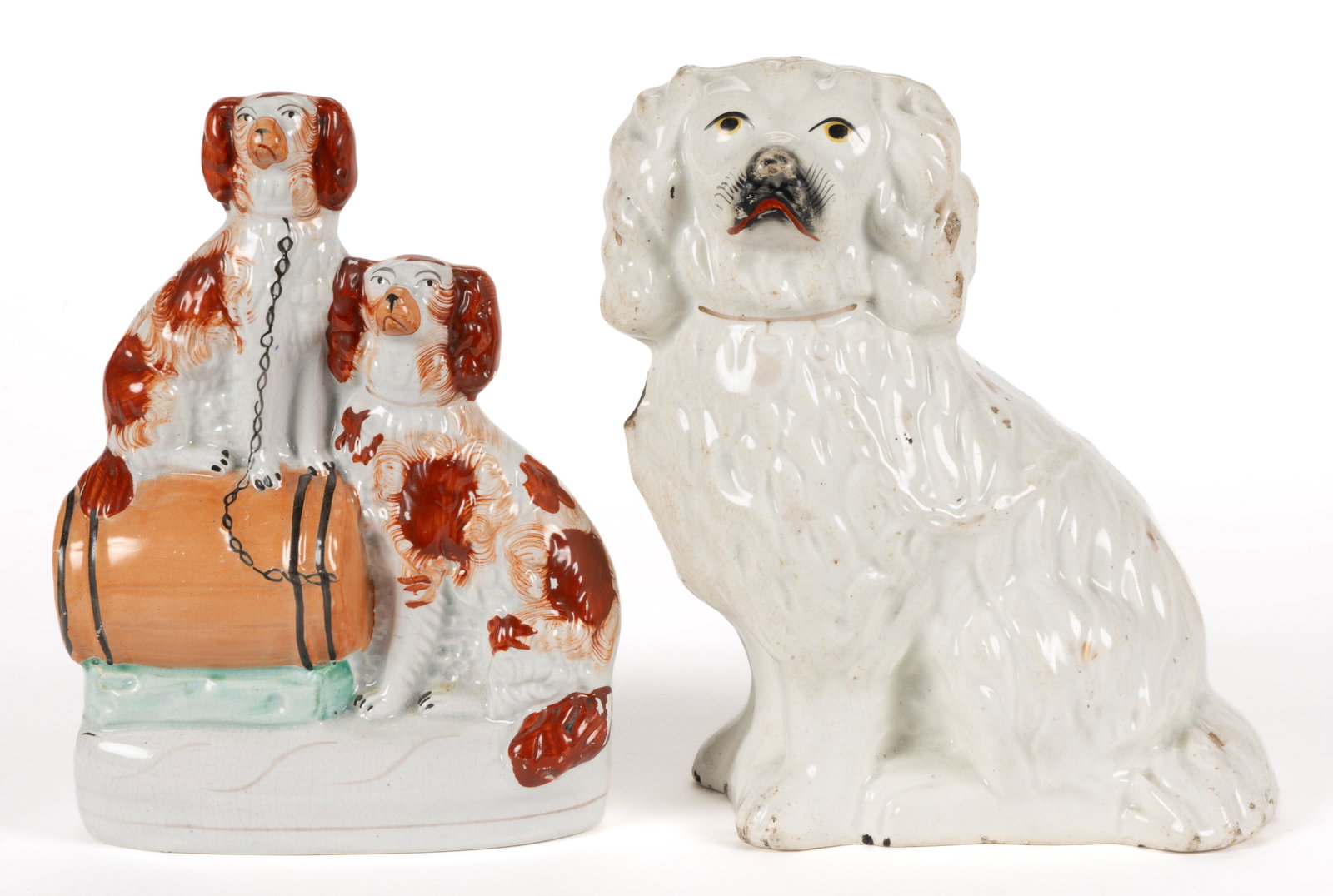 ENGLISH STAFFORDSHIRE HAND-PAINTED CERAMIC DOG FIGURES, LOT OF TWO: ENGLISH STAFFORDSHIRE HAND-PAINTED CERAMIC DOG FIGURES, LOT OF TWO, comprising a group on an ovoid base depicting two red-spotted spaniels including one sitting on top of a horizontal barrel and 