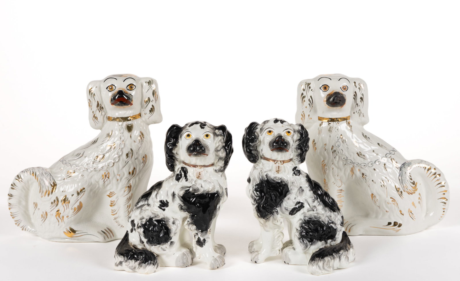 ENGLISH STAFFORDSHIRE HAND-PAINTED CERAMIC DOG PAIRS, LOT OF TWO: ENGLISH STAFFORDSHIRE HAND-PAINTED CERAMIC DOG PAIRS, LOT OF TWO, each depicting a sitting spaniel wearing a gilt collar and locket, comprising one black-spotted pair with separate front legs and one 