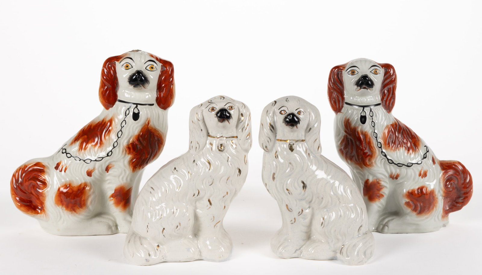 ENGLISH STAFFORDSHIRE HAND-PAINTED CERAMIC DOG PAIRS, LOT OF TWO: ENGLISH STAFFORDSHIRE HAND-PAINTED CERAMIC DOG PAIRS, LOT OF TWO, each depicting a sitting spaniel, comprising a red-spotted pair wearing a black collar with locket and chain and a gilt and white pair