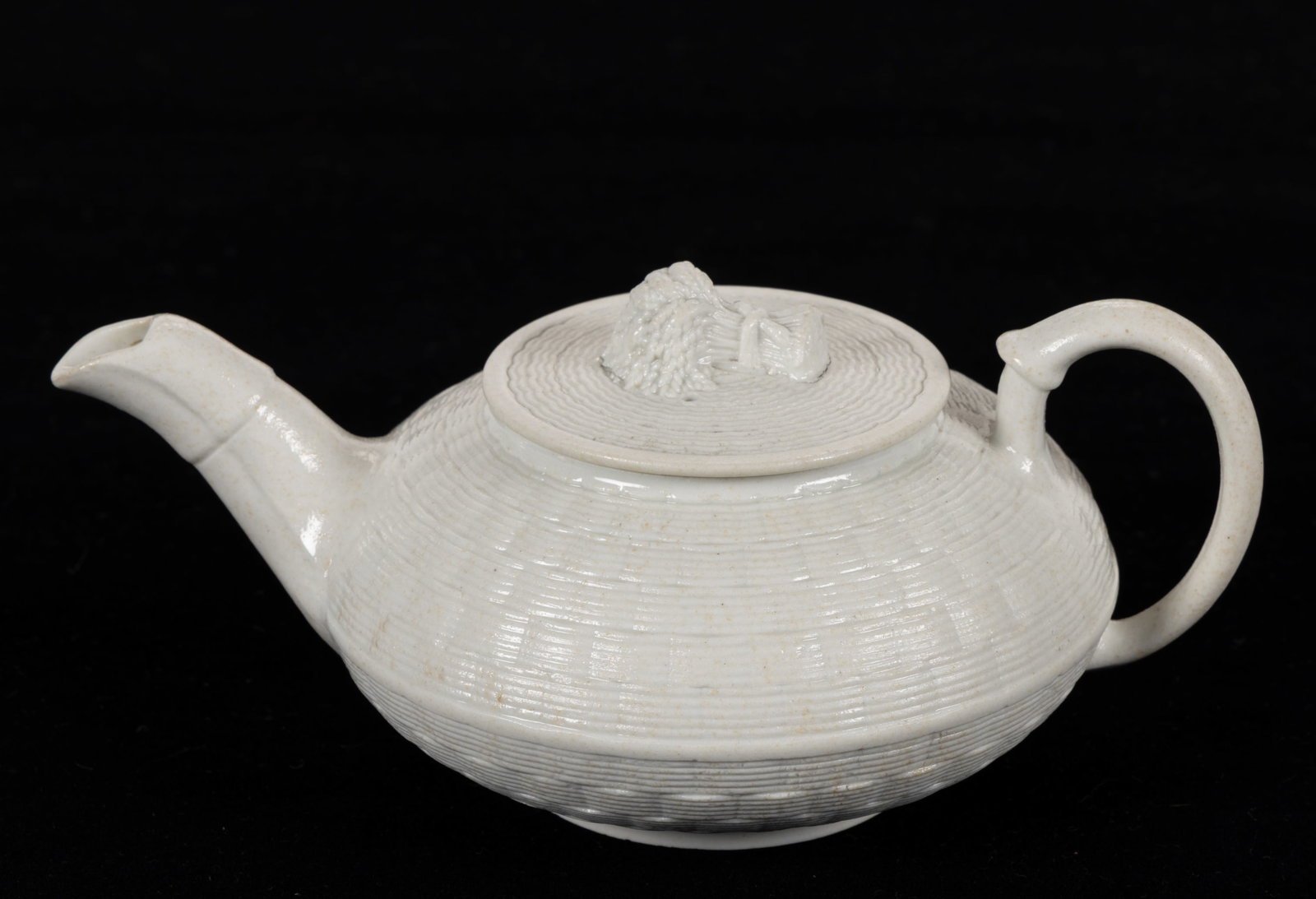 ENGLISH WEDGWOOD SMEAR-GLAZED STONEWARE DIMINUTIVE TEAPOT: ENGLISH WEDGWOOD SMEAR-GLAZED STONEWARE DIMINUTIVE TEAPOT, squat form, having molded basketweave body and cover with a figural sheaf of wheat finial. Impressed "WEDGWOOD" to unders