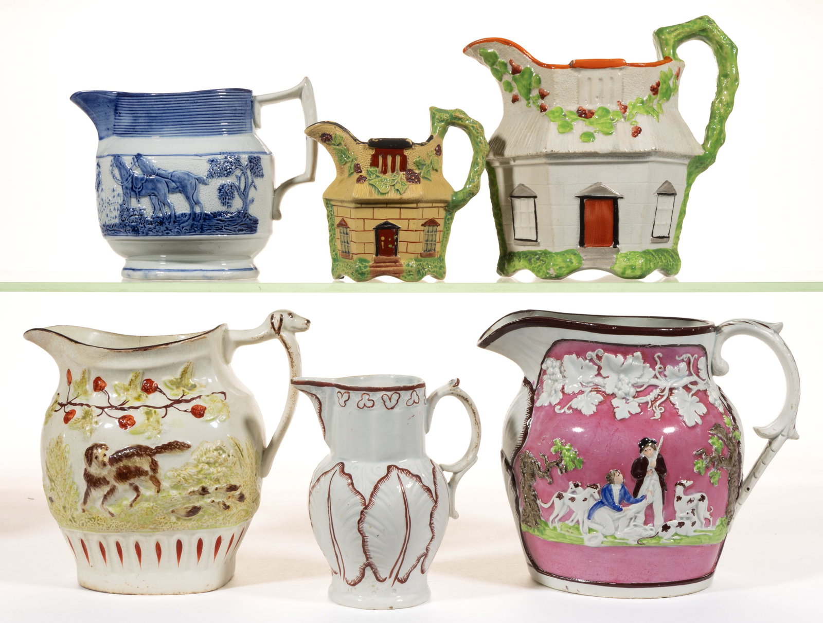 BRITISH RELIEF-MOLDED HAND-PAINTED CERAMIC JUGS / PITCHERS, LOT OF SIX: BRITISH RELIEF-MOLDED HAND-PAINTED CERAMIC JUGS / PITCHERS, LOT OF SIX, comprising one ovoid example featuring a blue-decorated hunt scene including horses and dogs, one baluster-form creamer with lar