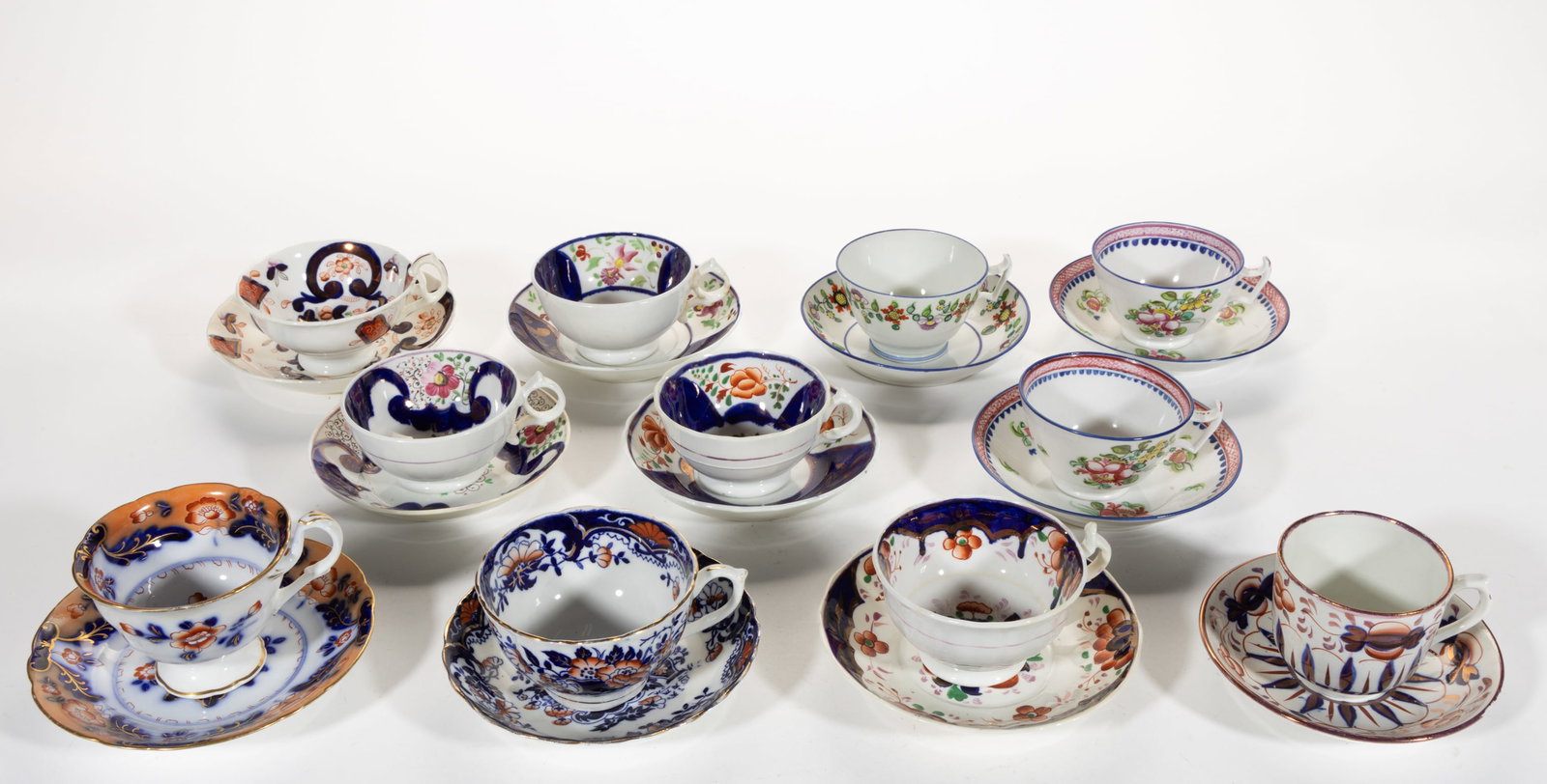 BRITISH HAND-PAINTED COBALT-DECORATED FLORAL MOTIF CERAMIC CUP AND SAUCER SETS, LOT OF 11: BRITISH HAND-PAINTED COBALT-DECORATED FLORAL MOTIF CERAMIC CUP AND SAUCER SETS, LOT OF 11, comprising three New Hall examples including two matching and each saucer having red circular "New / Hal