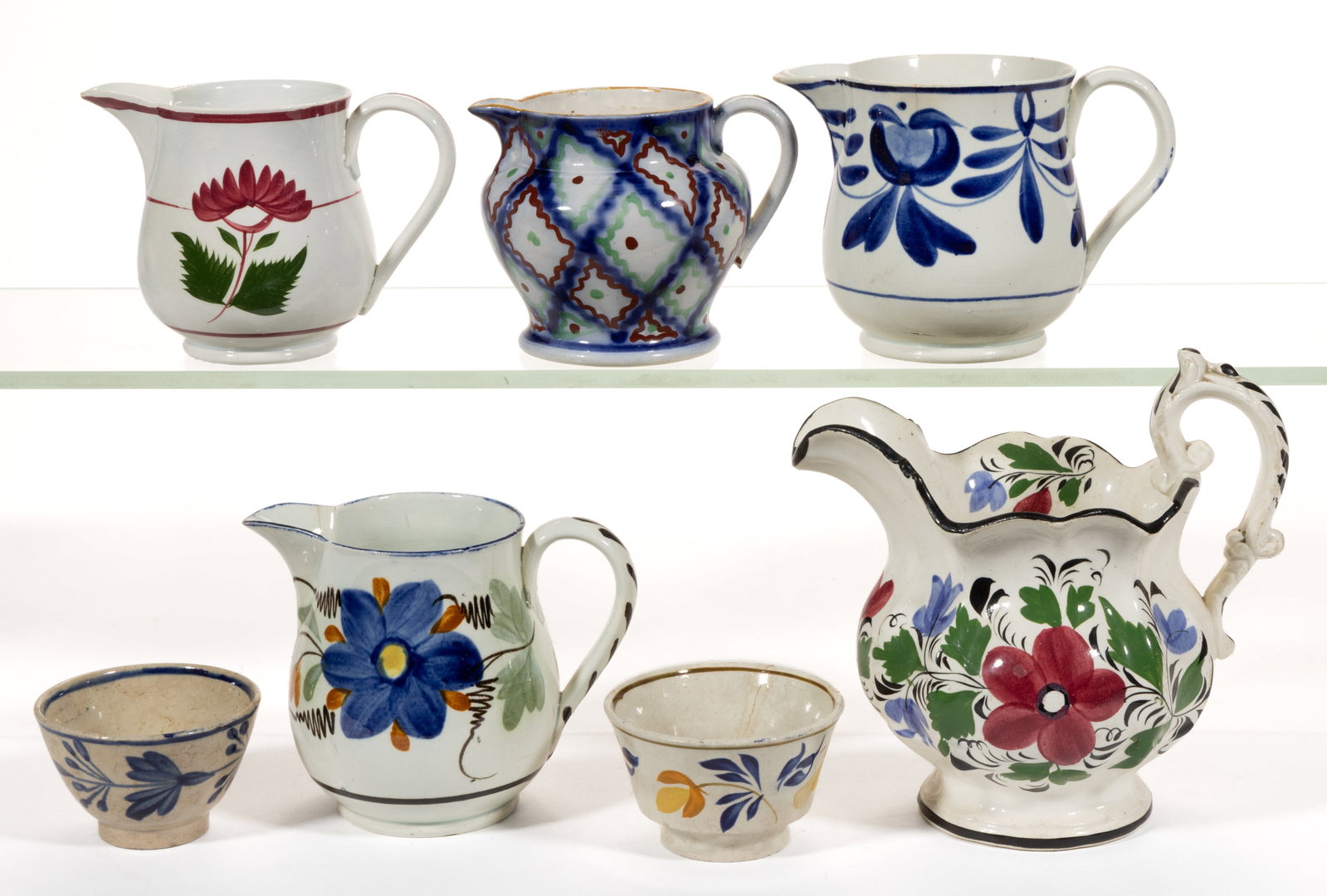 BRITISH HAND-PAINTED CERAMIC TEA ARTICLES, LOT OF SEVEN: BRITISH HAND-PAINTED CERAMIC TEA ARTICLES, LOT OF SEVEN, comprising two children's cups with floral motifs consisting of one with polychrome decoration and one having monochrome blue and five crea