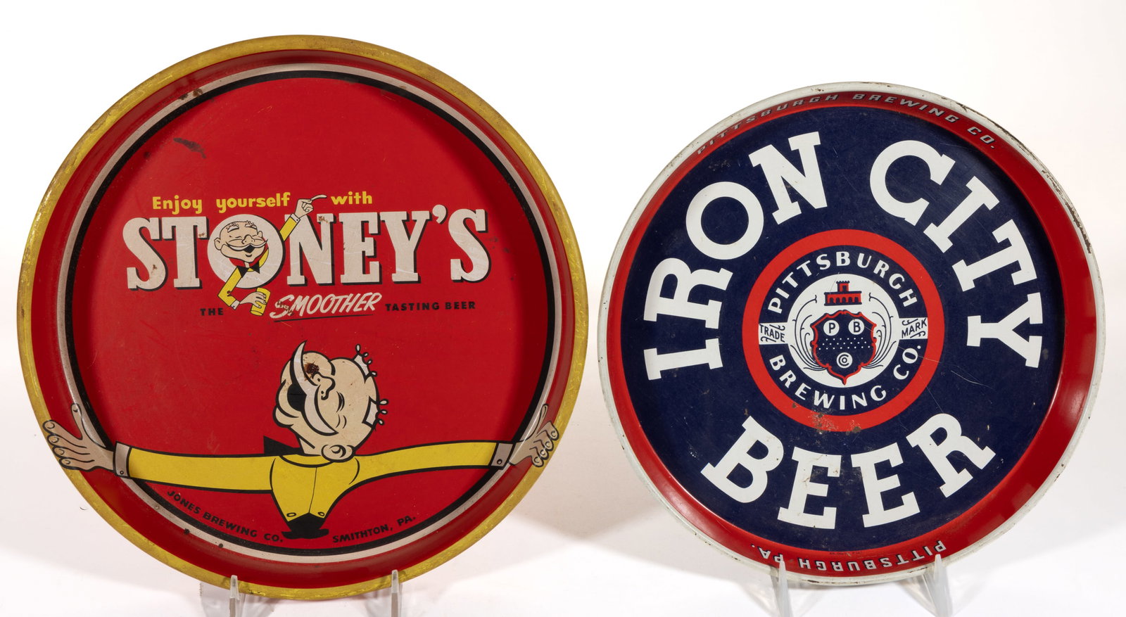 PENNSYLVANIA BREWERY TIN ADVERTISING TRAYS, LOT OF TWO: PENNSYLVANIA BREWERY TIN ADVERTISING TRAYS, LOT OF TWO, comprising an "IRON CITY" example from Pittsburgh and a "STONEY'S" example from Smithton. Mid 20th century. Larger examp