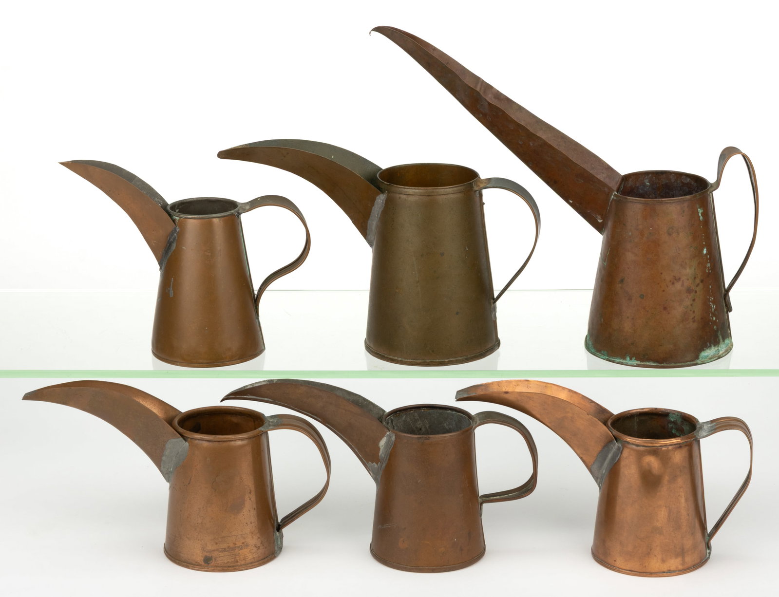 ASSORTED COPPER INK JUGS / PITCHERS, LOT OF SIX: ASSORTED COPPER INK JUGS / PITCHERS, LOT OF SIX, each of similar tapered conical form with an applied handle and an elongated so-called rooster or toucan pour spout. Supposedly used to fill inkwells i