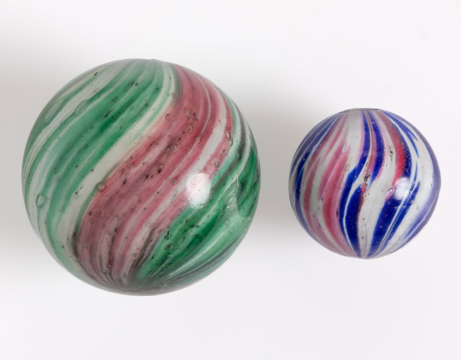 ANTIQUE SWIRLED ONIONSKIN GLASS MARBLES, LOT OF TWO: ANTIQUE SWIRLED ONIONSKIN GLASS MARBLES, LOT OF TWO, each having four-lobes with one having red and cobalt blue over white, and the other having red and green over white. Various makers