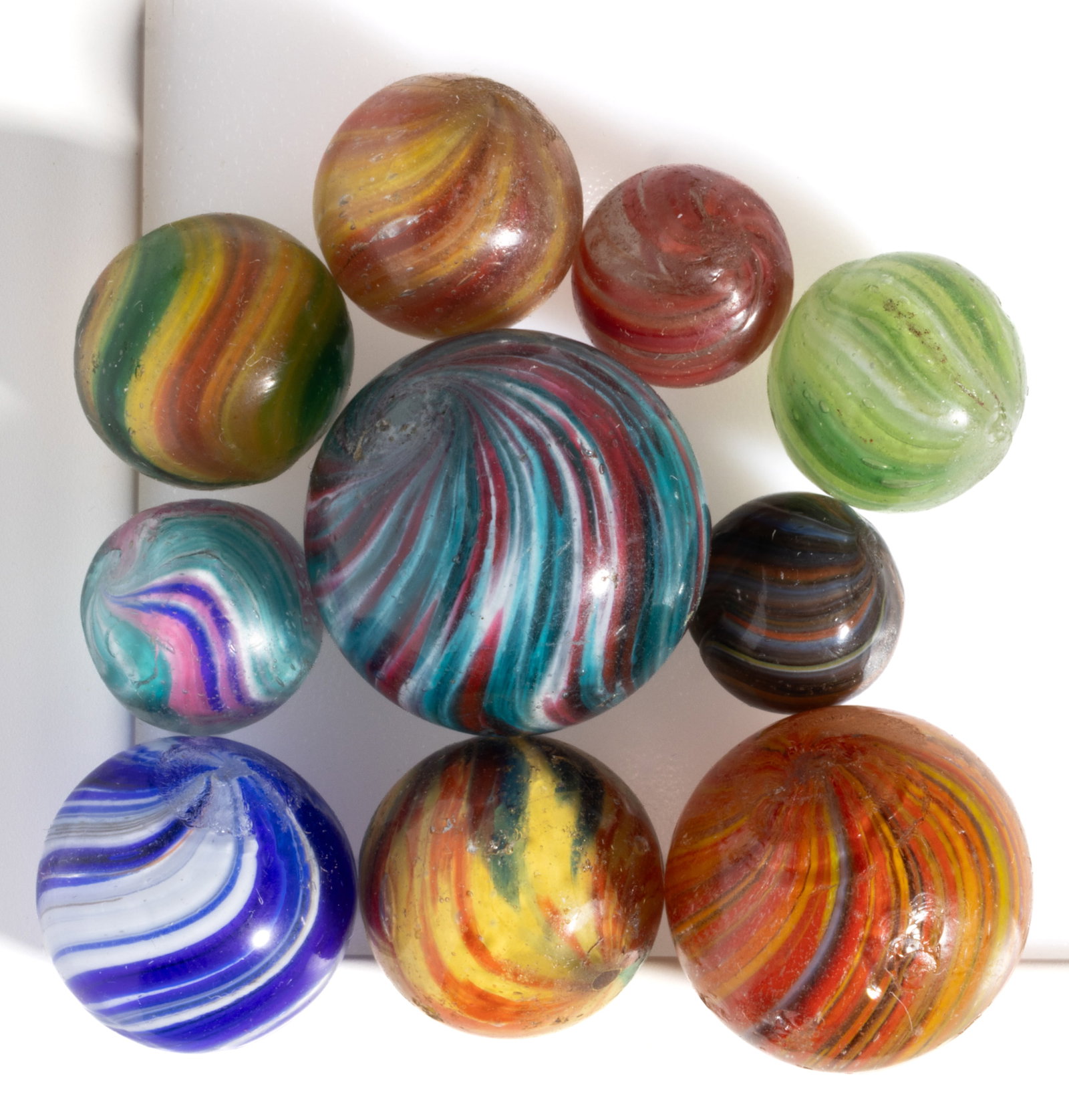 ANTIQUE ONIONSKIN MARBLES, LOT OF TEN: ANTIQUE ONIONSKIN MARBLES, LOT OF TEN, each multi-colored, colors including yellow, red, green, blue, white, and orange, including one with a slightly shrunken core. Various makers. Late