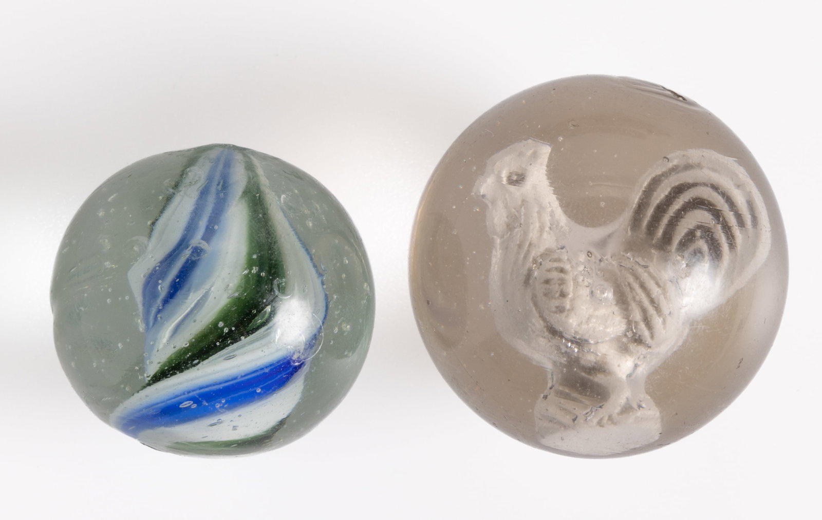 ANTIQUE GLASS MARBLES, LOT OF TWO: ANTIQUE GLASS MARBLES, LOT OF TWO, comprising a rooster sulphide and a transparent solid three-color core swirl marble. Various makers. Late 19th/early 20th century. 1 3/8" and 1 1