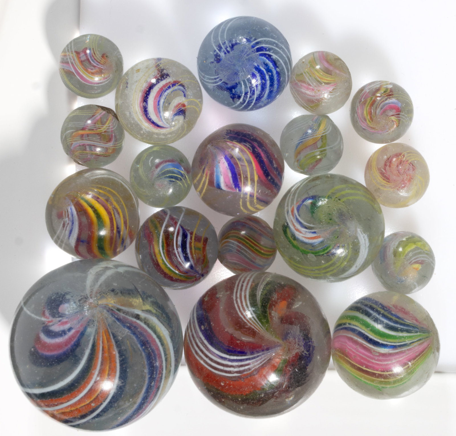 ANTIQUE TRANSPARENT SWIRL DIVIDED CORE GLASS MARBLES, LOT OF 18: ANTIQUE TRANSPARENT SWIRL DIVIDED CORE GLASS MARBLES, LOT OF 18, interior cores and exterior swirls having a variety of colors and combinations. Various makers. Late 19th/early 20th century.