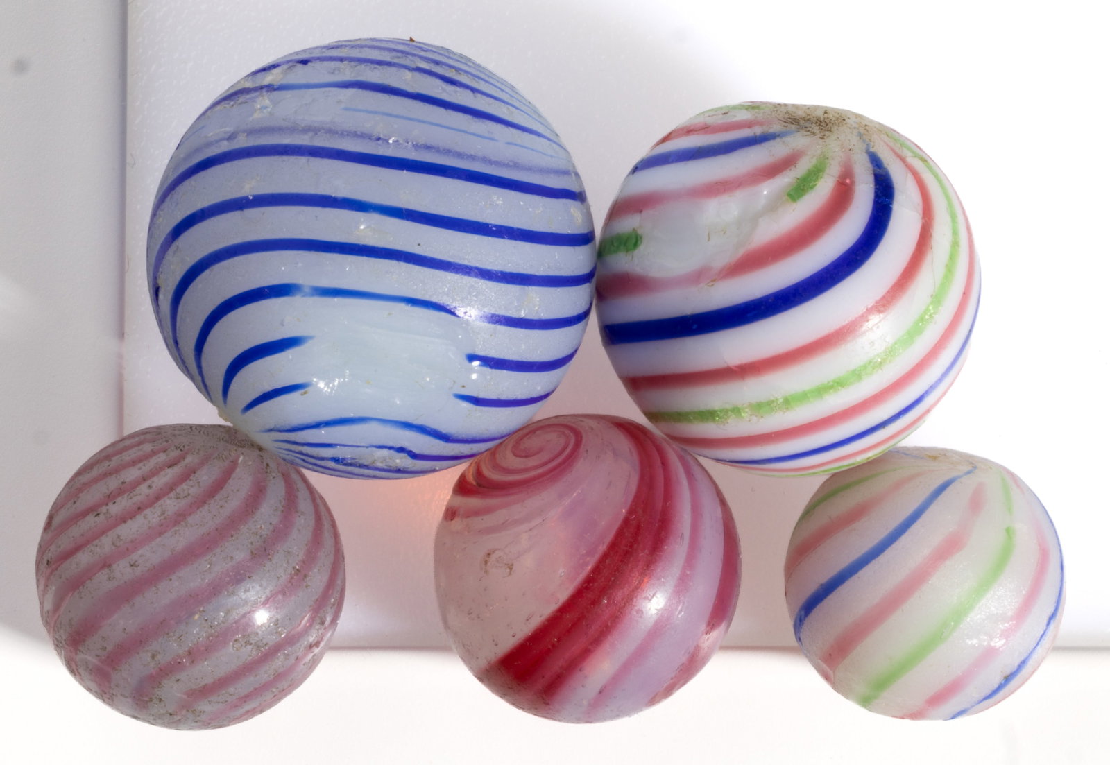 ASSORTED HAND BLOWN CLAMBROTH SWIRL MARBLES, LOT OF FIVE: ASSORTED HAND BLOWN CLAMBROTH SWIRL MARBLES, LOT OF FIVE, including two with alternating red, blue, and green threads, and one with pink bands, each having rough pontil marks. Various m