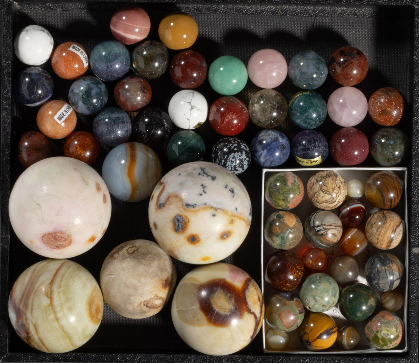 ASSORTED STONE MARBLES, LOT OF 58: ASSORTED STONE MARBLES, LOT OF 58, including a Red Goldstone, jasper, black snowflake obsidian, mahogany obsidian, and banded agate examples. Various makers. 20th century. 3/8" to 2" D. Prov