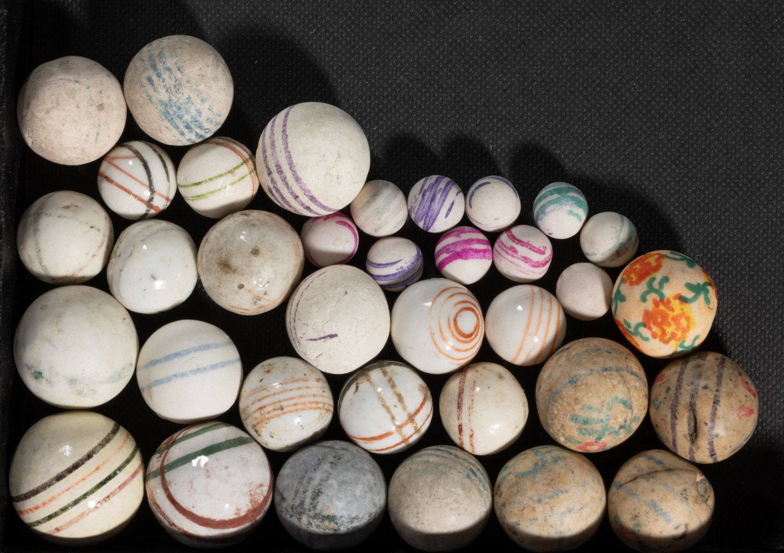 HAND-PAINTED CHINA MARBLES, LOT OF 35: HAND-PAINTED CHINA MARBLES, LOT OF 35, including "bull's eye", intersecting lines, and a myriad of other designs, glazed and unglazed. Various makers. 19th century. 3/8" to