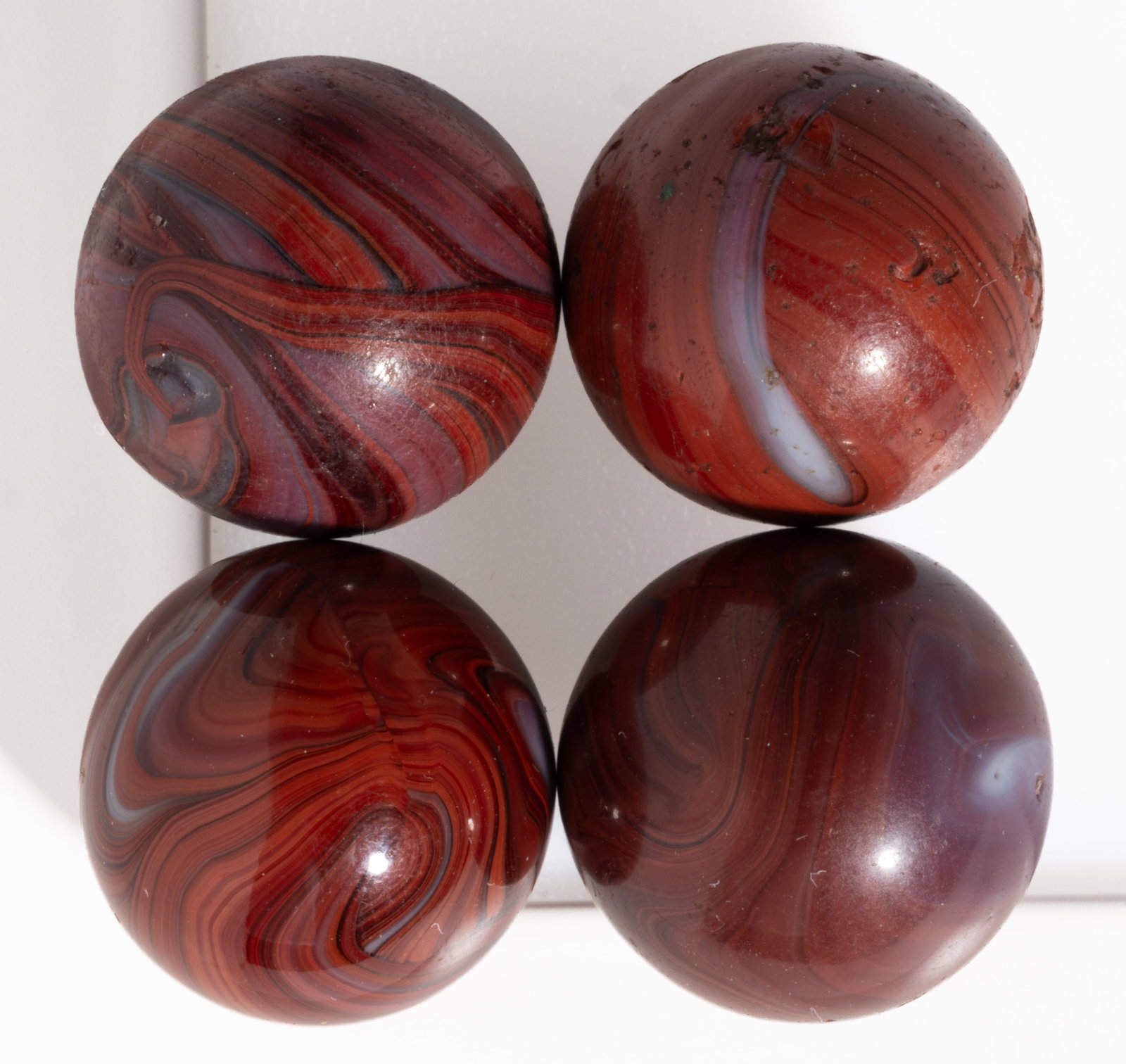 M. F. CHRISTENSEN BRICK MACHINE-MADE MARBLES, LOT OF FOUR: M. F. CHRISTENSEN BRICK MACHINE-MADE MARBLES, LOT OF FOUR, each having oxblood, opaque white, and black swirls. M. F. Christensen & Son Co. 1910-1924. 11/16" to 3/4" D. Pr
