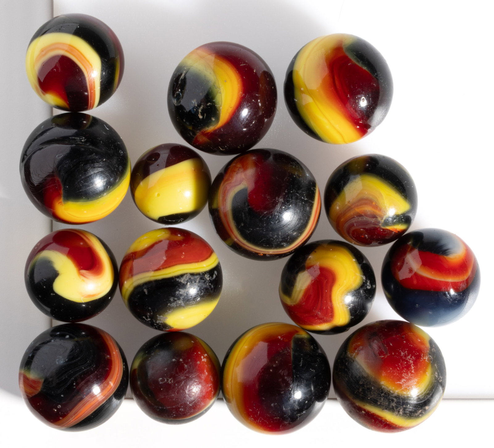 AKRO AGATE CORKSCREW INDIAN BLANKET MACHINE-MADE MARBLES, LOT OF 15: AKRO AGATE CORKSCREW INDIAN BLANKET MACHINE-MADE MARBLES, LOT OF 15, opaque black base color with red and yellow corkscrews. Akro Agate Co. 1925-1935. 19/32" to 13/16" D. Provenance: Fr