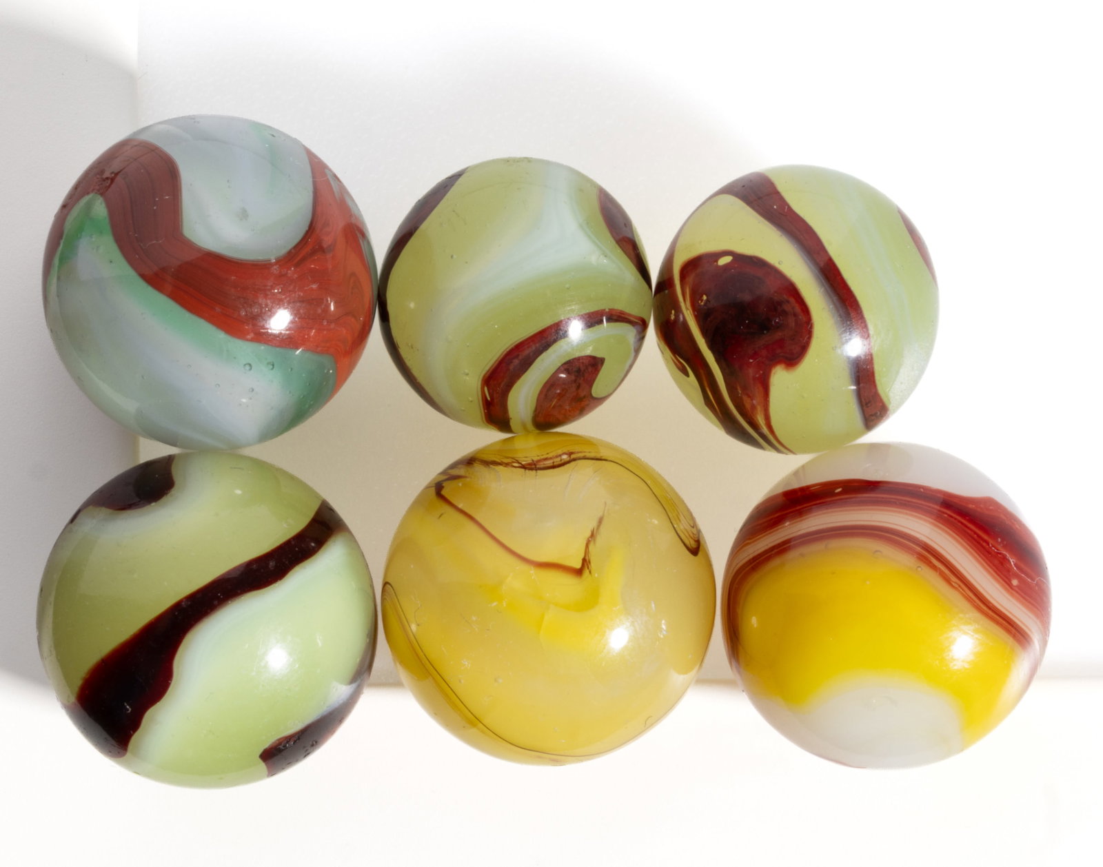 ASSORTED OXBLOOD MACHINE-MADE MARBLES, LOT OF SIX: ASSORTED OXBLOOD MACHINE-MADE MARBLES, LOT OF SIX, including three Lemonade oxbloods and an Egg Yolk oxblood. Akro Agate Co. and others. Second quarter 20th century. 5/8" to 3/4&qu