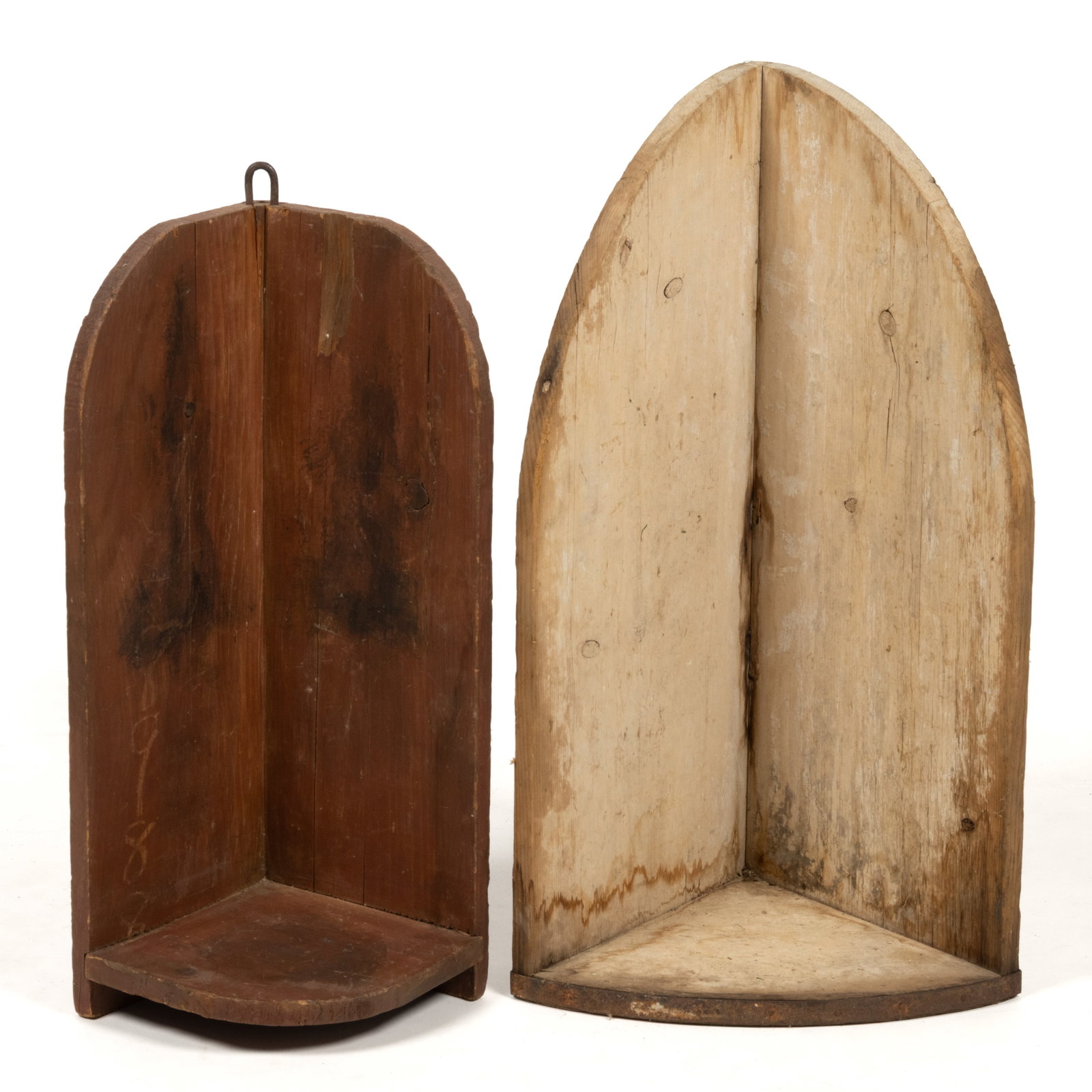 AMERICAN PAINTED PINE HANGING CORNER SHELVES, LOT OF TWO: AMERICAN PAINTED PINE HANGING CORNER SHELVES, LOT OF TWO, nailed construction, each of similar form with arched top edges and a rounded lower shelf, the larger with a piece of sheet-iron on the front