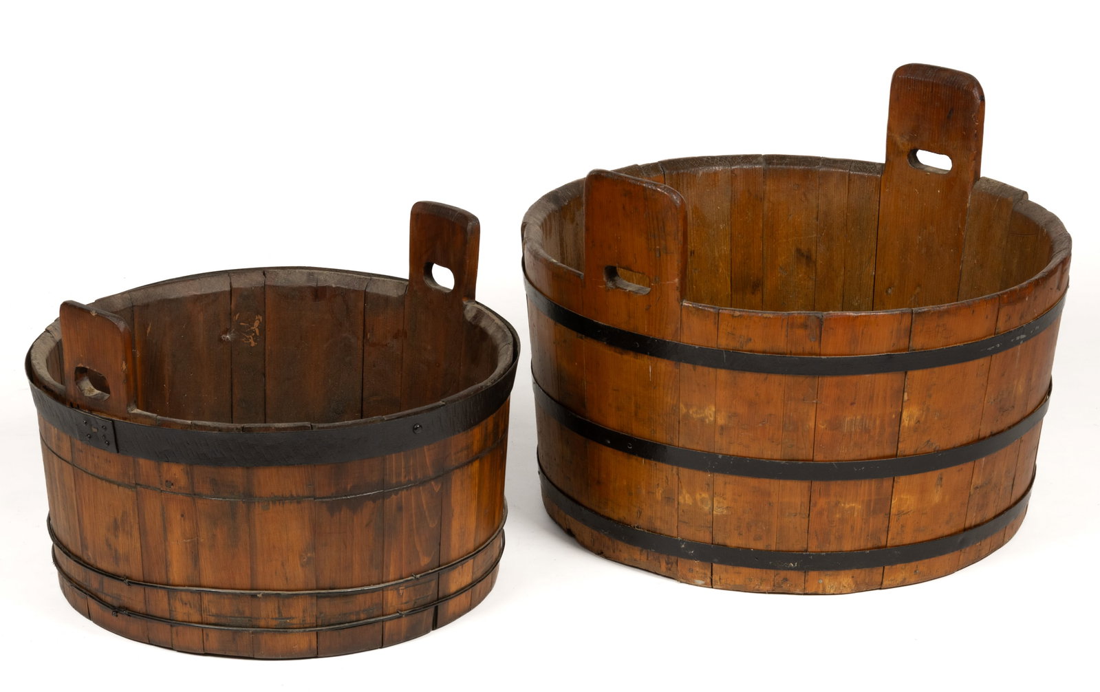 AMERICAN PINE WASH TUBS, LOT OF TWO: AMERICAN PINE WASH TUBS, LOT OF TWO, each of staved form with iron bands and raised tab handles. Both retain a later finished surface. Second half 19th century. Largest 18" HOA, 13" H rim, 2