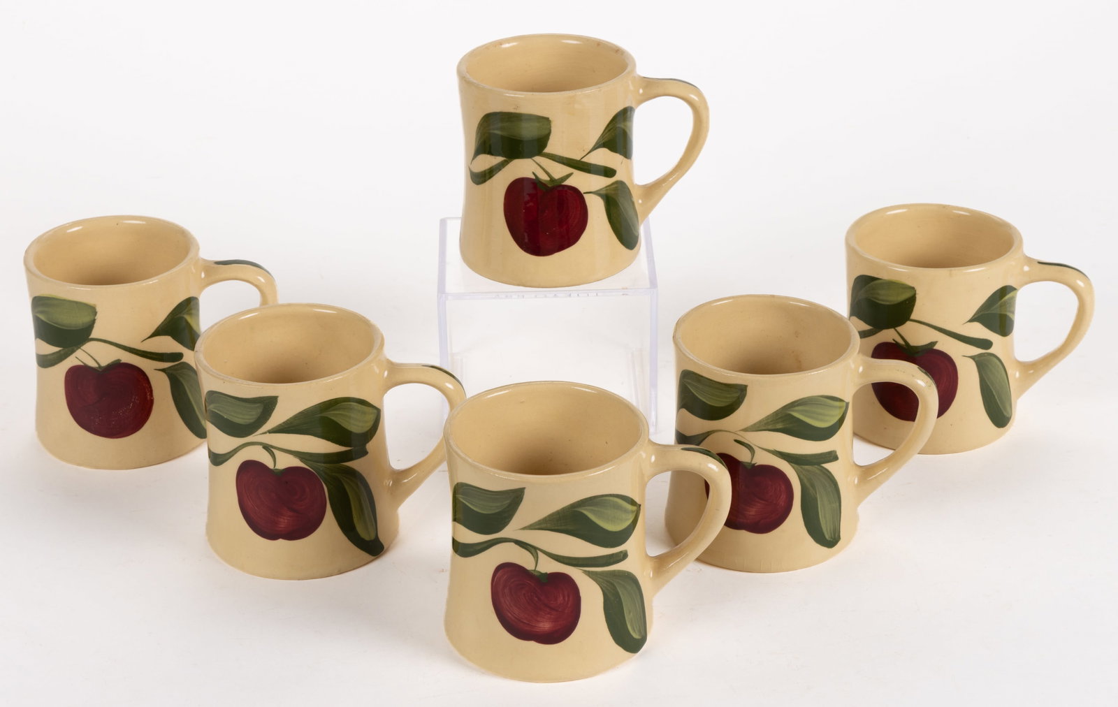 WATT POTTERY NO. 121 "APPLE" MUGS, SET OF SIX: WATT POTTERY NO. 121 "APPLE" MUGS, SET OF SIX, each having a slight hour-glass form, each with apple and foliage decoration, bases impressed in a circle "WATT / 121 / U. S.