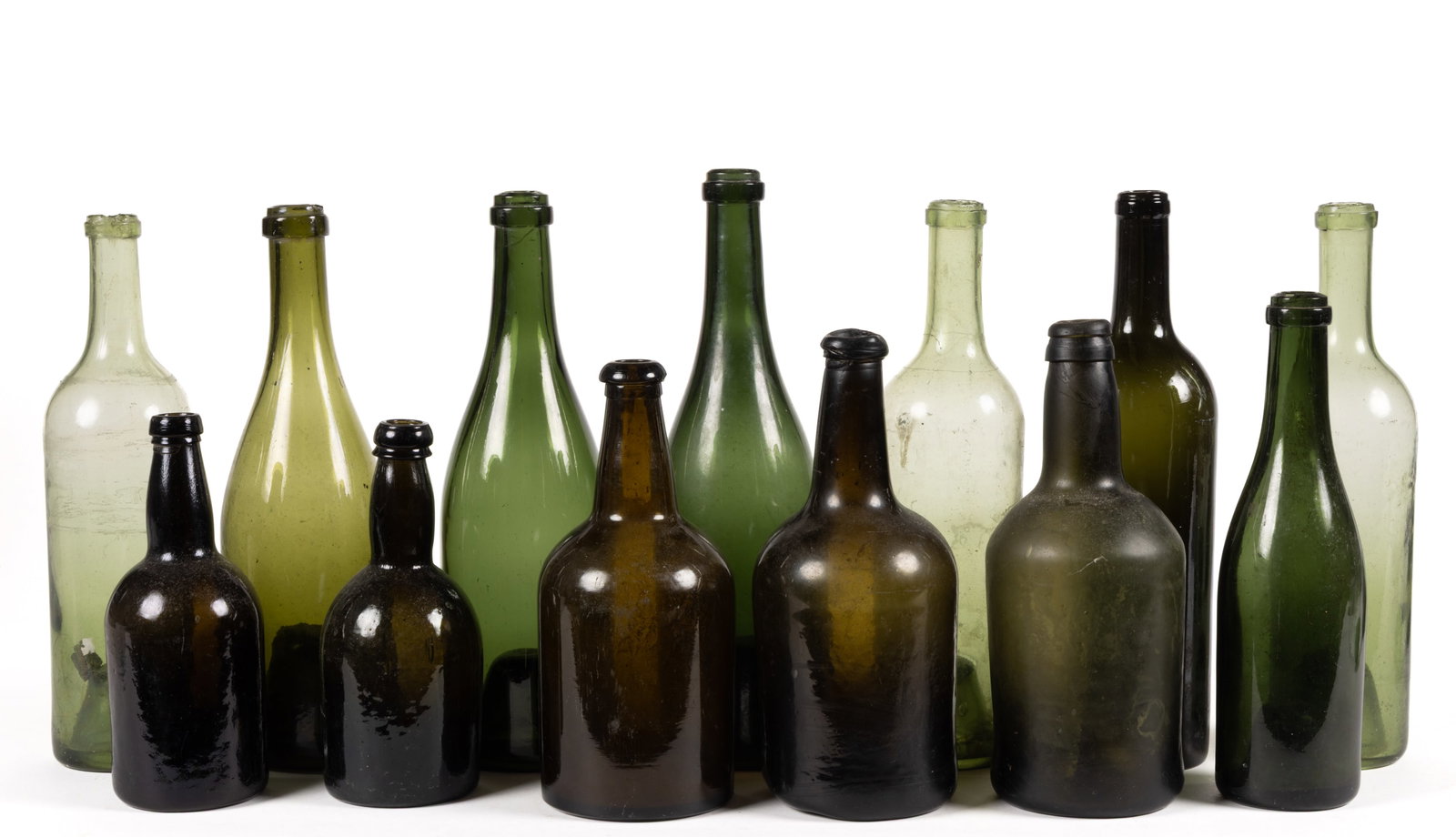 ASSORTED BLACK GLASS LIQUOR / WINE AND OTHER UTILITY BOTTLES, LOT OF 13: ASSORTED BLACK GLASS LIQUOR / WINE AND OTHER UTILITY BOTTLES, LOT OF 13, shades of light to dark olive-green/black glass, blown-molded in various forms with assorted lip treatments, each with kick-up 