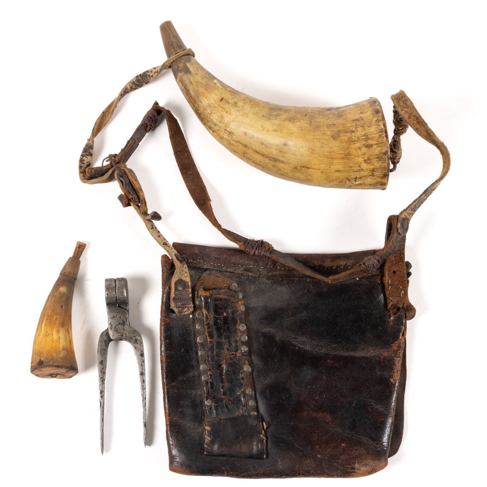 AMERICAN FRONTIER HUNTING BAG AND ACCOUTREMENTS: AMERICAN FRONTIER HUNTING BAG AND ACCOUTREMENTS, the leather bag with original flap and partial original leather strap, hung with a powder horn, along with a primer horn and iron scissor-typ