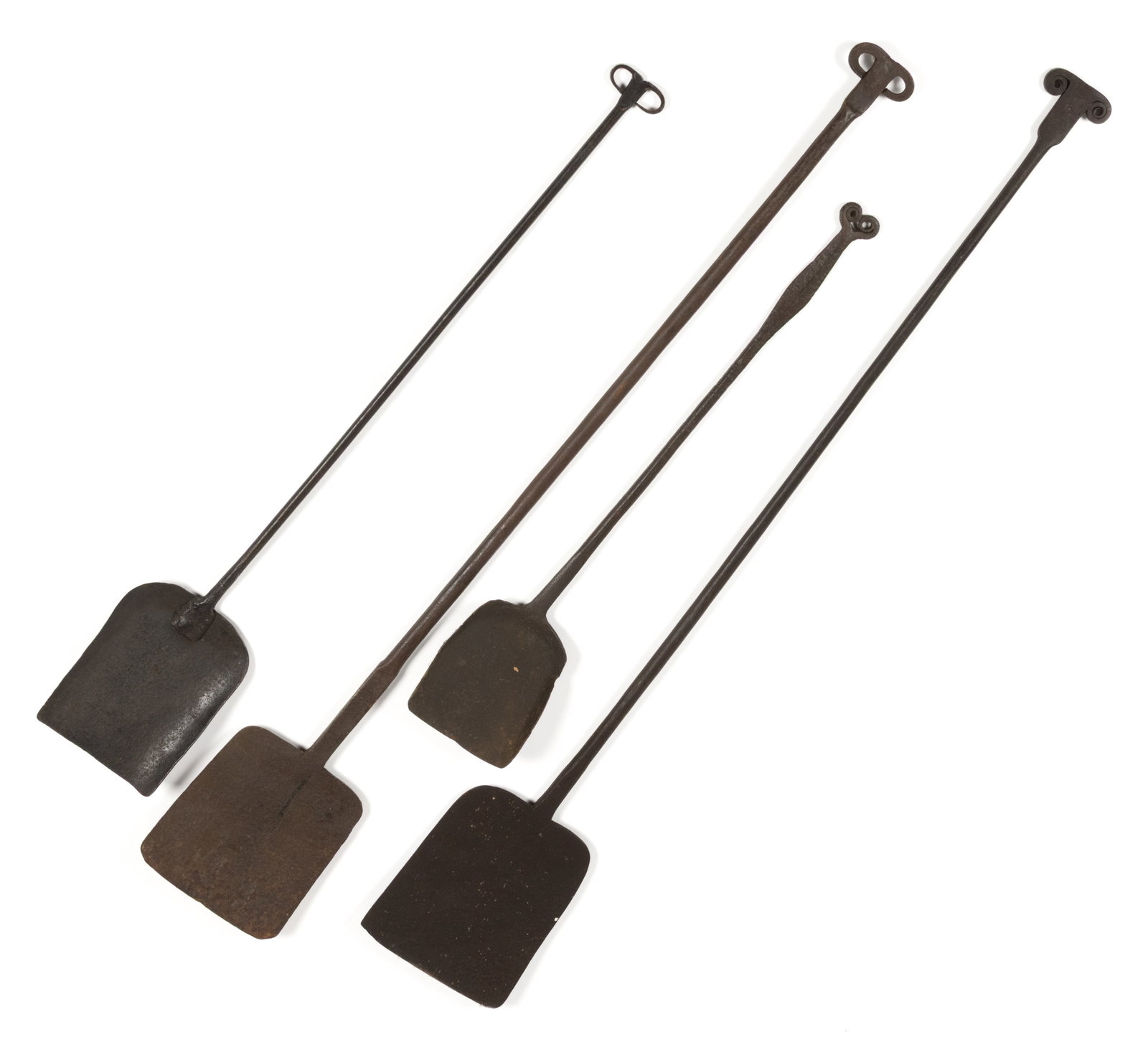 ASSORTED WROUGHT-IRON HEARTH AND FIREPLACE PEELS, LOT OF FOUR: ASSORTED WROUGHT-IRON HEARTH AND FIREPLACE PEELS, LOT OF FOUR, each having a rams head horn handle extension, one example with a flat-bladed handle. 18th/19th century. 26 1/4" to