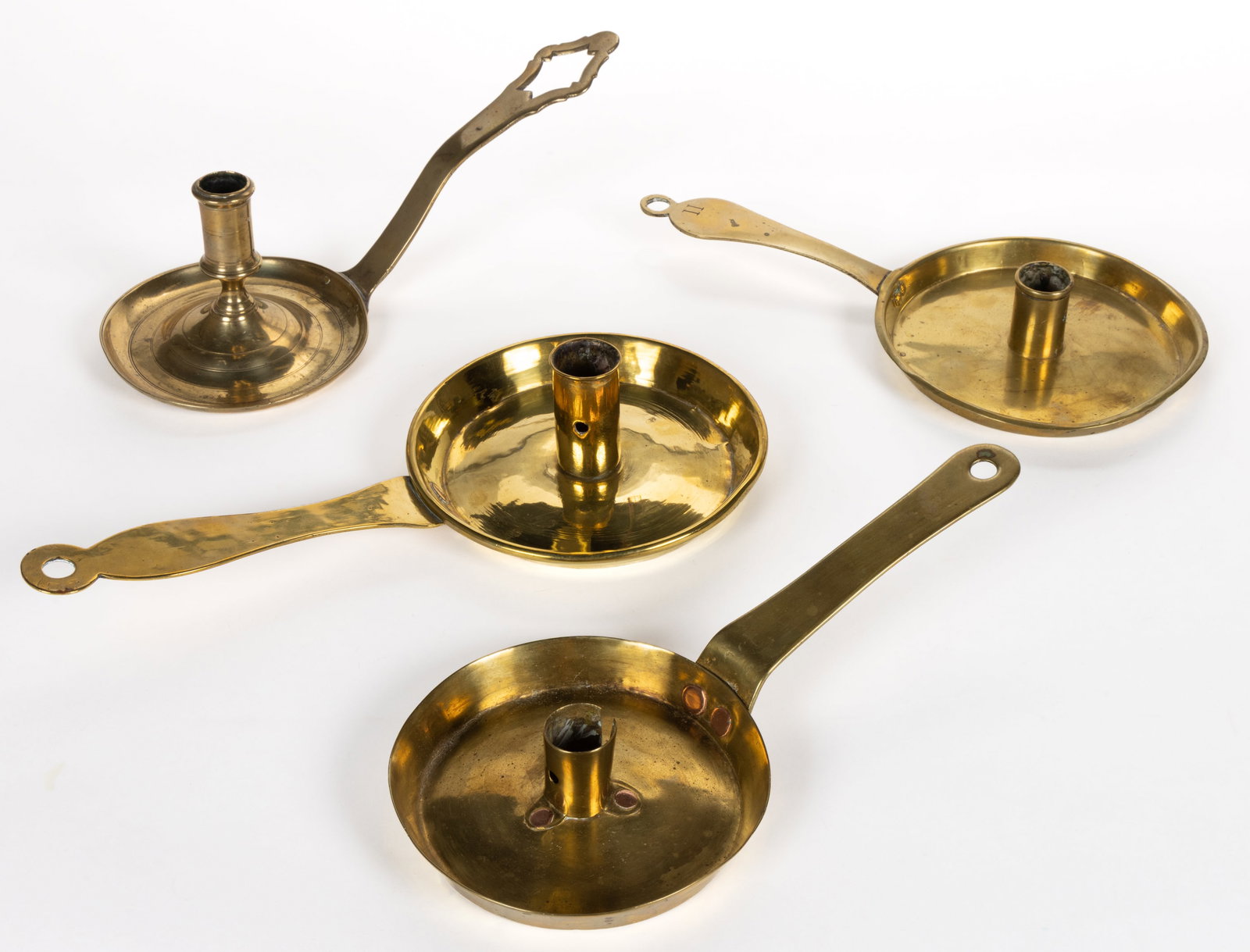 ASSORTED BRASS CHAMBERSTICK CANDLEHOLDERS, LOT OF FOUR: ASSORTED BRASS CHAMBERSTICK CANDLEHOLDERS, LOT OF FOUR, each with a saucer base, handle, and a single socket, comprising of three examples with the handle having a ring tip and riveted socke