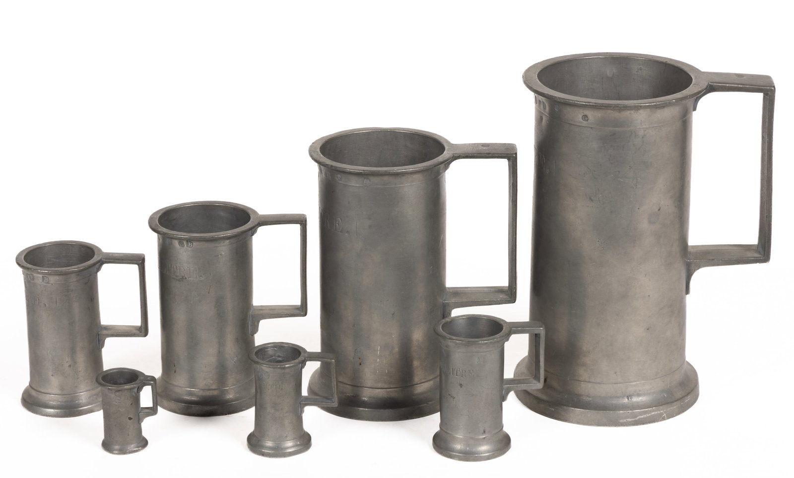 ASSORTED PEWTER MEASURERS, ASSEMBLED SET OF SEVEN: ASSORTED PEWTER MEASURERS, ASSEMBLED SET OF SEVEN, each cylinder forms with each having a square-form handle, five examples having a touchmark of an eagle over "C. M. & Co." to the under