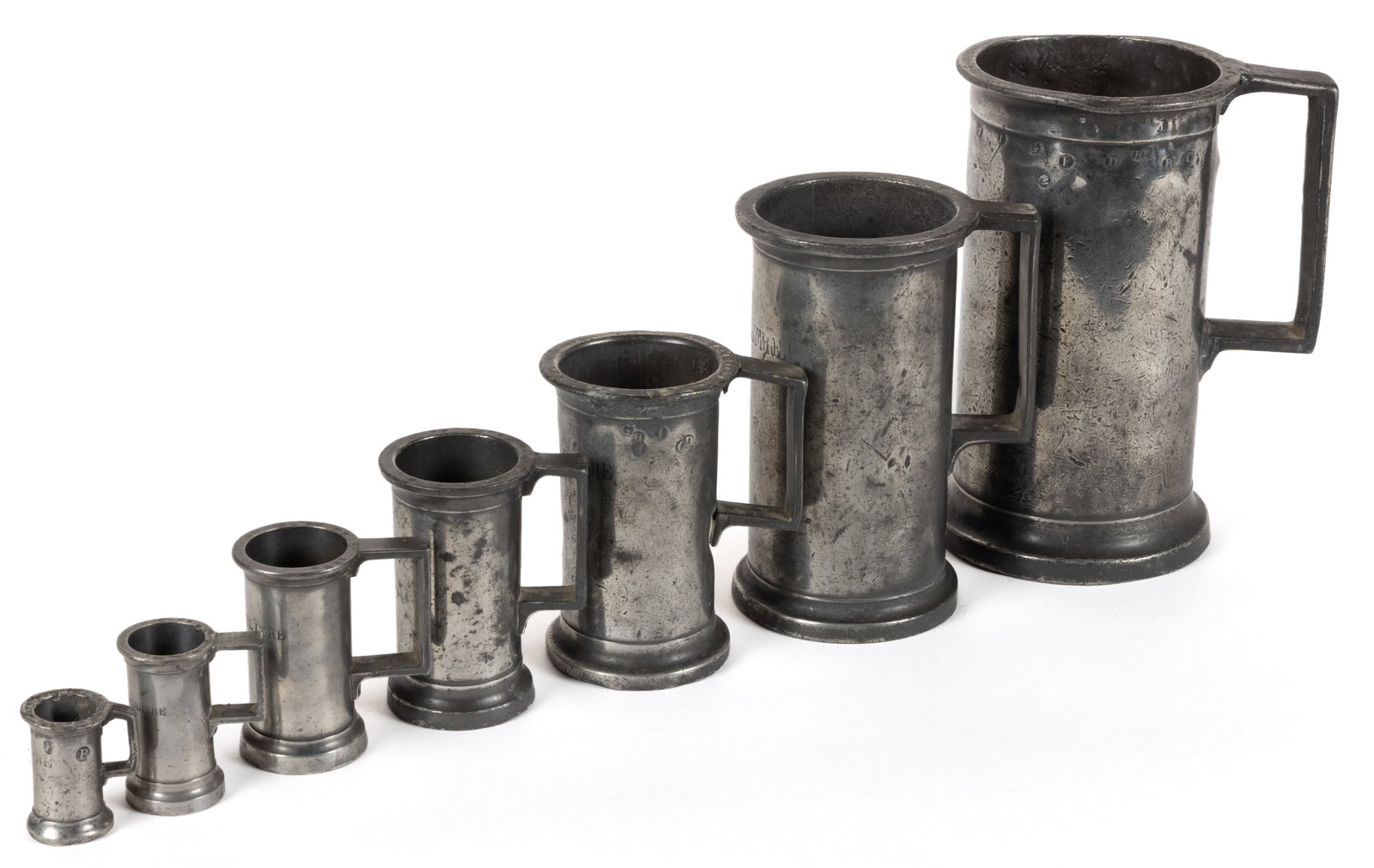 ASSORTED FRENCH PEWTER MEASURERS / UN ENSEMBLE DE HUIT MESURES METRIQUES, ASSEMBLED SET OF SIX: ASSORTED FRENCH PEWTER MEASURERS / UN ENSEMBLE DE HUIT MESURES METRIQUES, ASSEMBLED SET OF SIX, each with open top and handle, sizes include centilitre, double centilitre, demi-decilitre, de