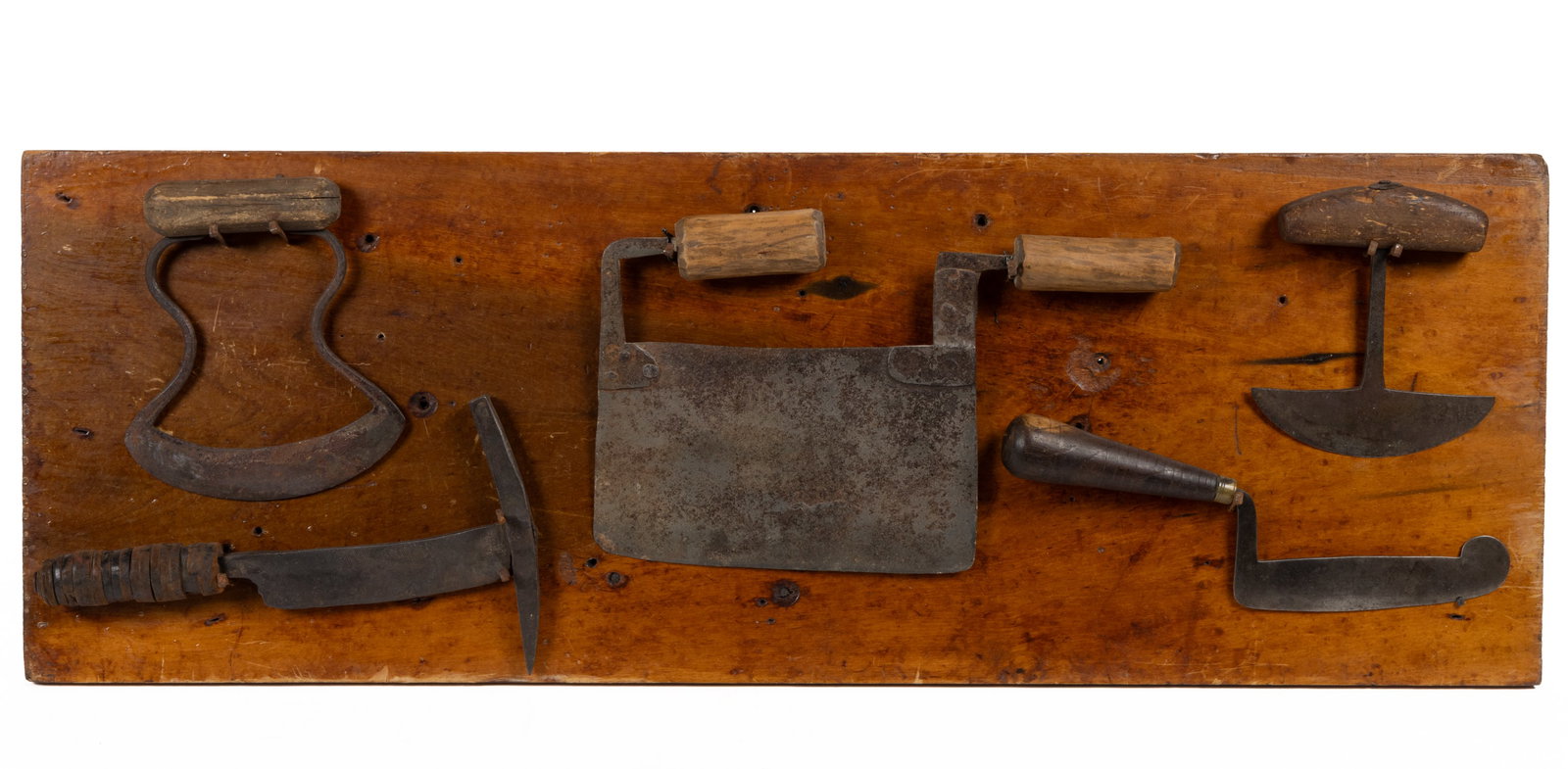 AMERICAN WROUGHT-IRON HOOD CHOPPERS AND ASSOCIATED TOOLS, LOT OF FIVE PRESENTED ON A BOARD: AMERICAN WROUGHT-IRON HOOD CHOPPERS AND ASSOCIATED TOOLS, LOT OF FIVE PRESENTED ON A BOARD, including a so-called bubble and squeak chopper with a rounded end; typical rounded-edge food choppers; and 