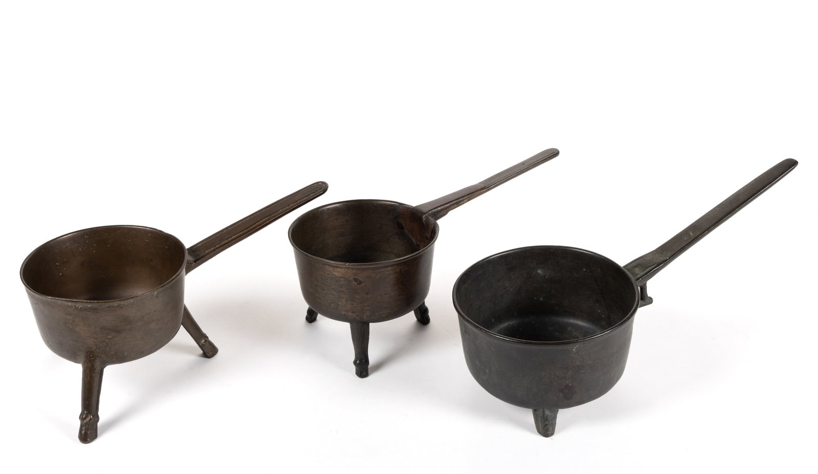 ASSORTED BRONZE BRAZIERS / POSNETS, LOT OF THREE: ASSORTED BRONZE BRAZIERS / POSNETS, LOT OF THREE, each raised on three legs with handle and two examples having a circular-form sprue mark to the underside, comprising of an example