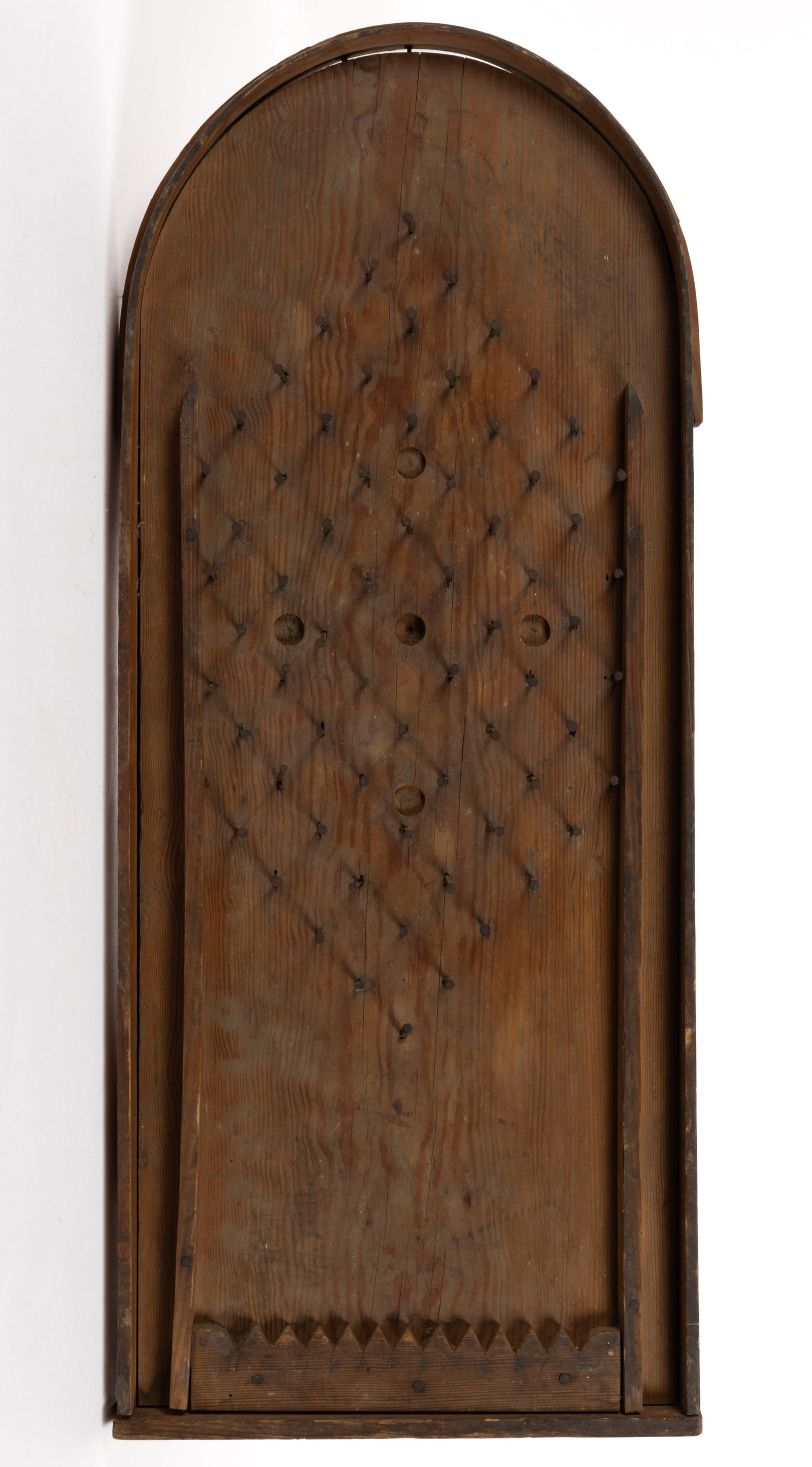 SHENANDOAH VALLEY OF VIRGINIA YELLOW PINE MARBLE GAME: SHENANDOAH VALLEY OF VIRGINIA YELLOW PINE MARBLE GAME, nailed construction, tombstone-form yellow pine plank with bentwood gallery housing a central field of square cut nails, the bottom with a sawtoo