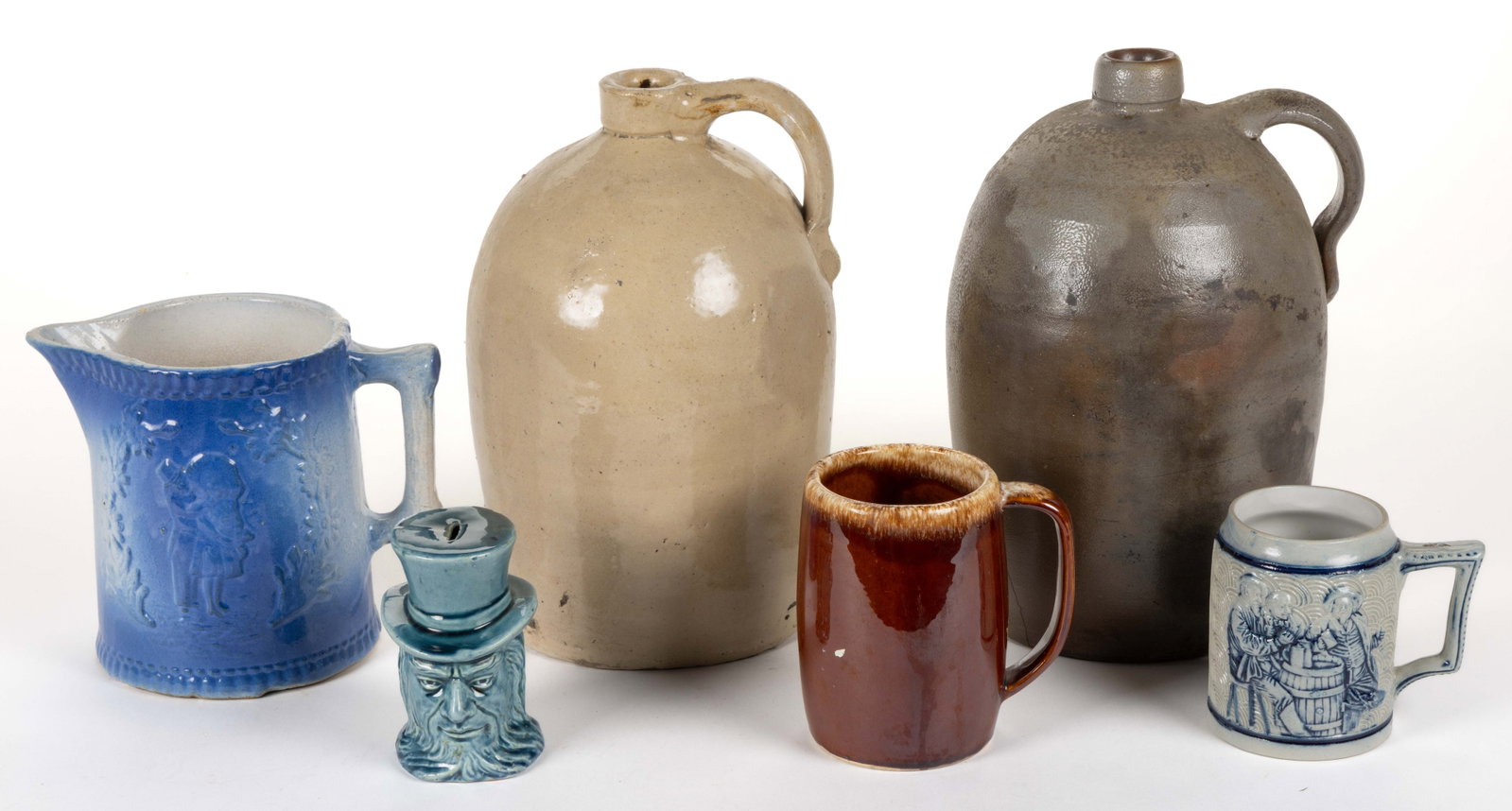ASSORTED POTTERY DOMESTIC ARTICLES, LOT OF SIX: ASSORTED POTTERY DOMESTIC ARTICLES, LOT OF SIX, including a stamped Whites Pottery, Utica, NY beer stein featuring buffalo and three drinking men, an Uncle Sam head money bank, a blue and white salt-g