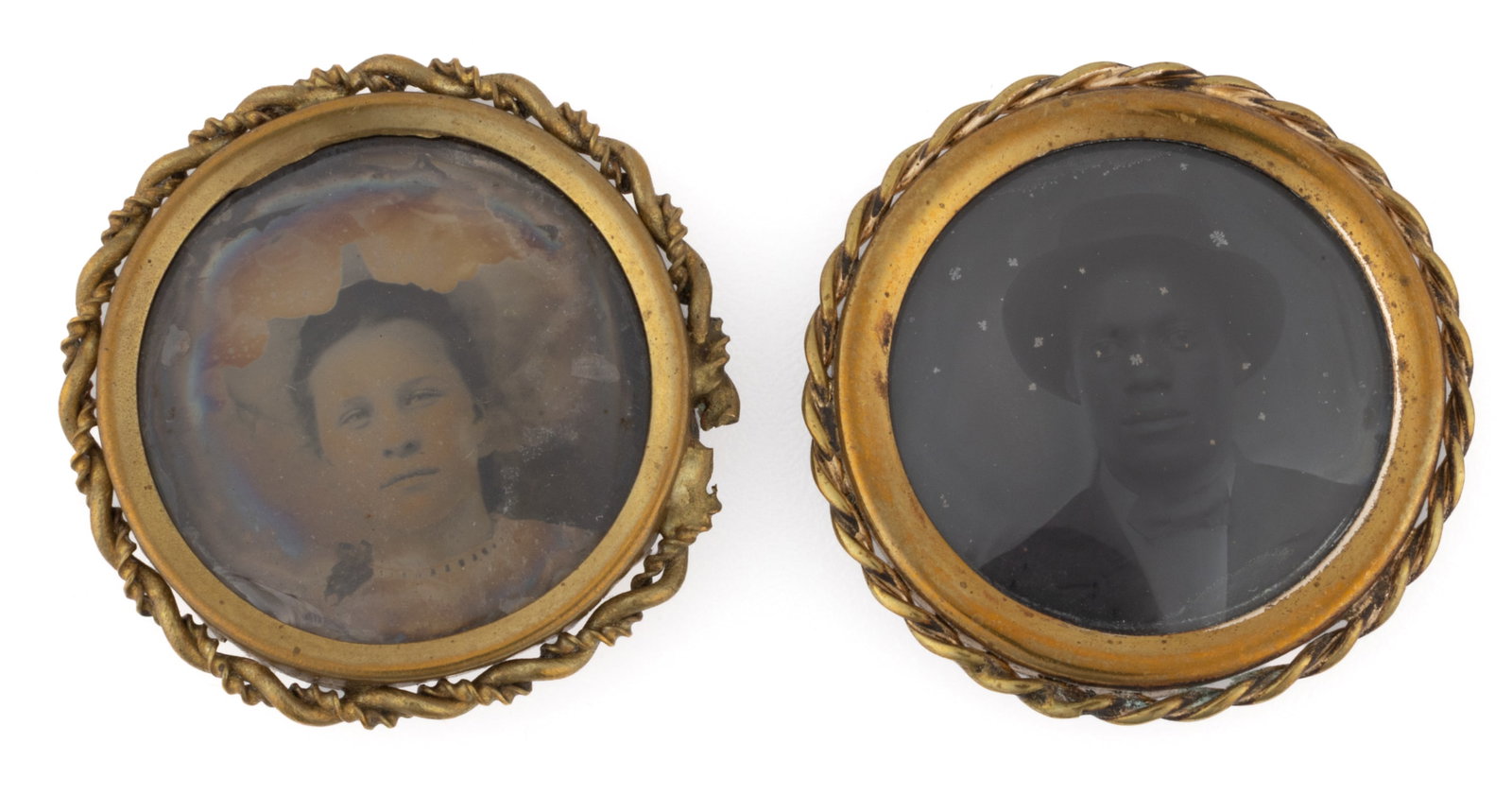 AFRICAN-AMERICAN PORTRAIT TINTYPE BROOCHES, NEAR PAIR: AFRICAN-AMERICAN PORTRAIT TINTYPE BROOCHES, NEAR PAIR, near-matching gold-filled frames with pin backs, one with the bust of a young man wearing a suit and a hat, the other of a young lady w
