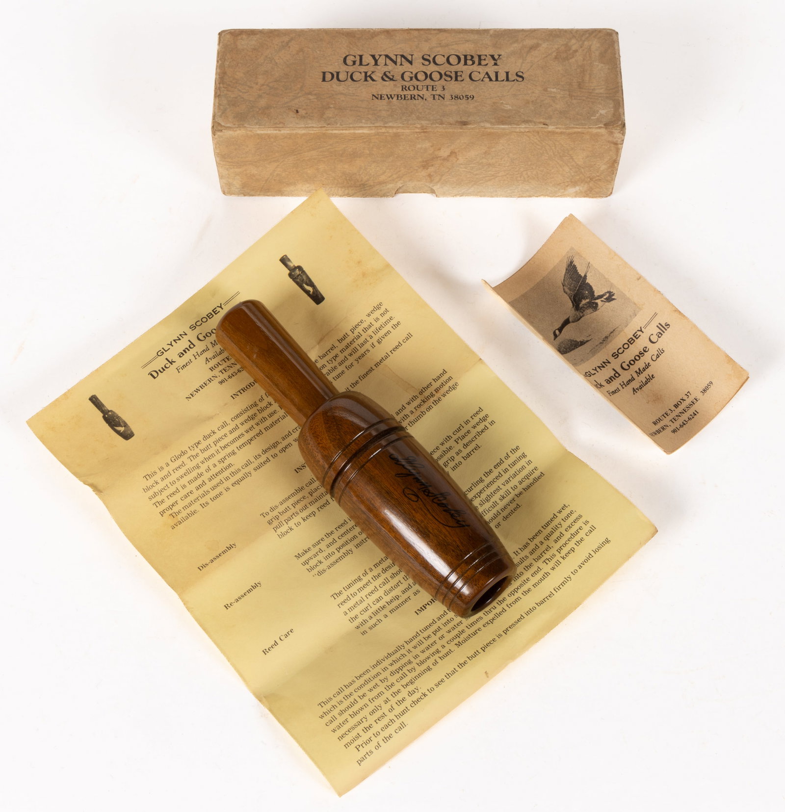 GLYNN SCOBEY (TENNESSEE, 1932-2011) SIGNATURE DUCK / GOOSE CALL: GLYNN SCOBEY (TENNESSEE, 1932-2011) SIGNATURE DUCK / GOOSE CALL, walnut with signature to the barrel, retains original instruction booklet, sheet, and box with Rouith 3 address. Object 6 3/8"
