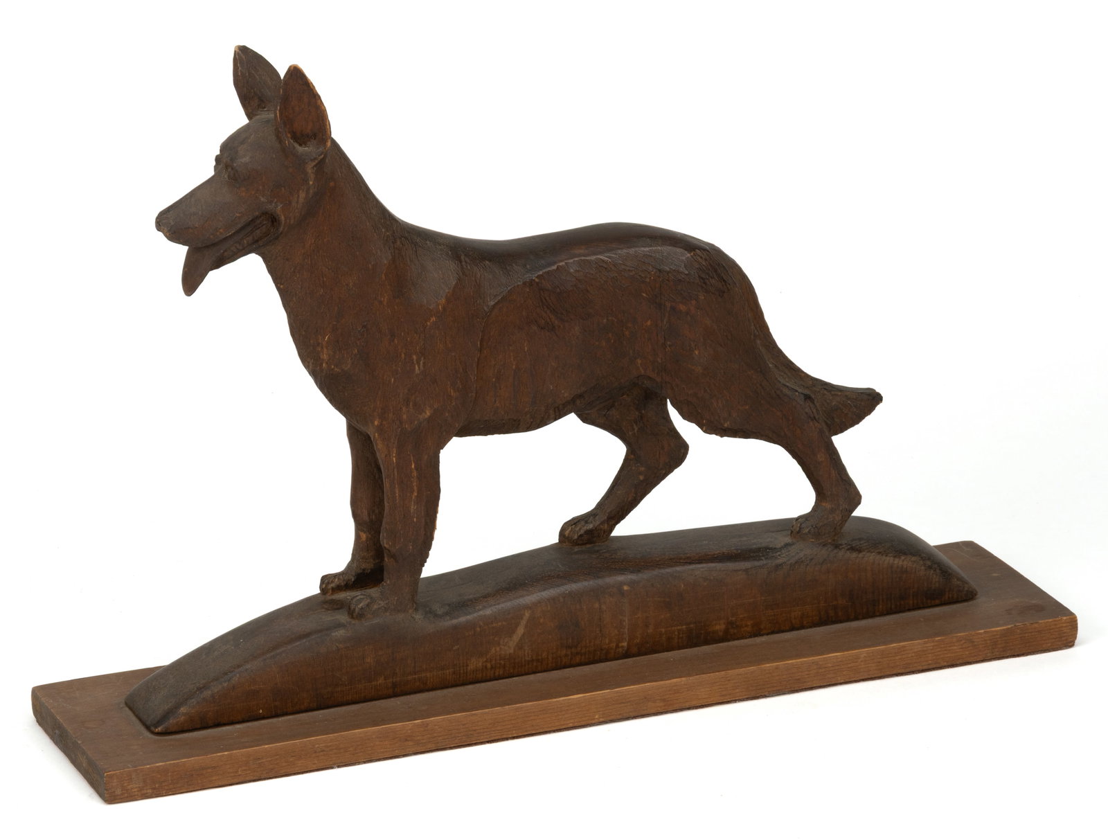 AMERICAN, POSSIBLY MARYLAND, FOLK ART CARVED PINE FIGURE OF A DOG: AMERICAN, POSSIBLY MARYLAND, FOLK ART CARVED PINE FIGURE OF A DOG, of solid form, depicting a large dog, possibly a German Shepherd standing on a mound, the whole mounted to a pine plank board. Retain