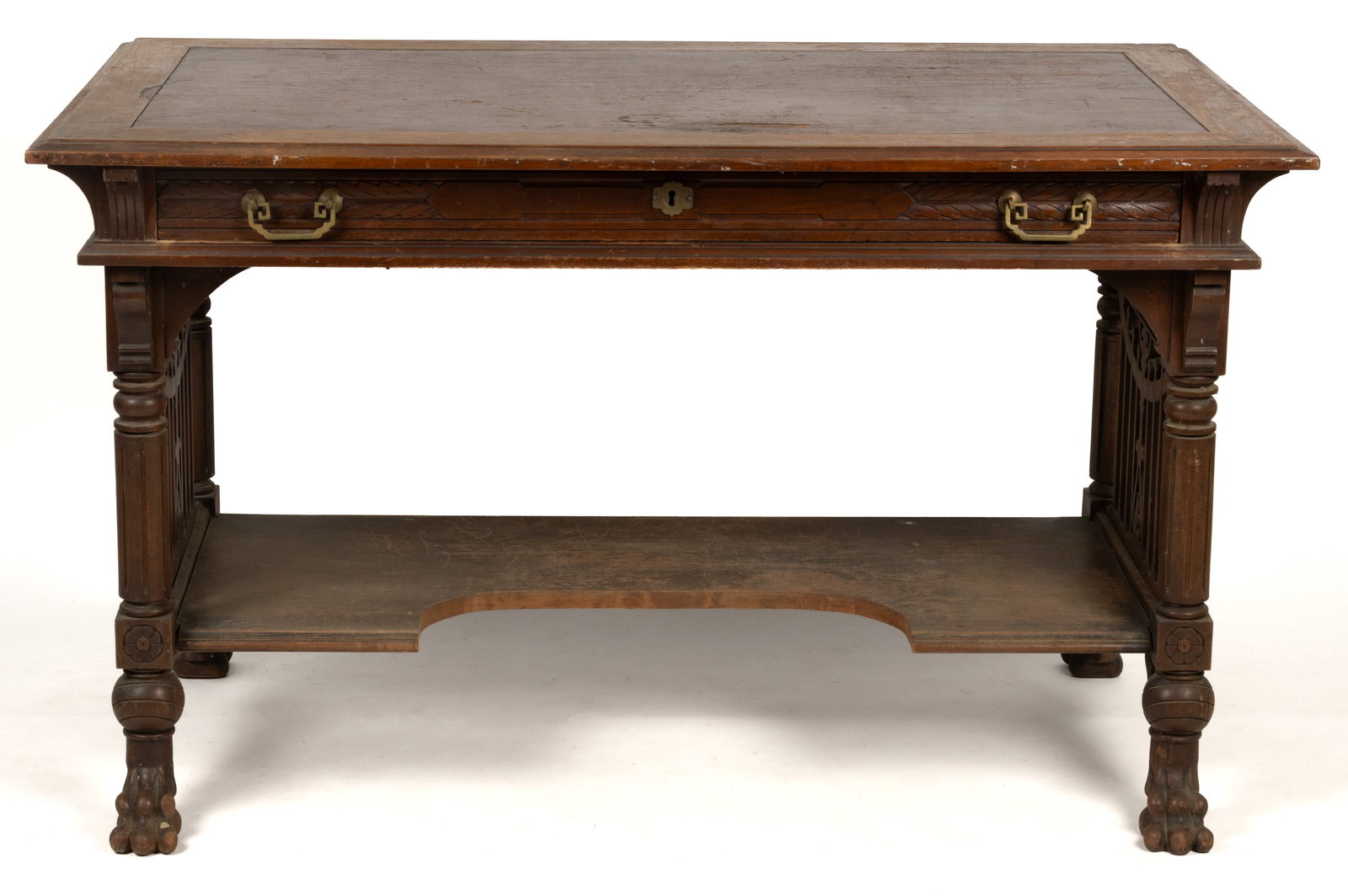 AMERICAN CARVED WALNUT WRITING DESK: AMERICAN CARVED WALNUT WRITING DESK, featuring molded-edge top with inset leather writing surface, full drawer retaining original brass pulls, and turned legs ending in stylized paw feet, stenciled ma