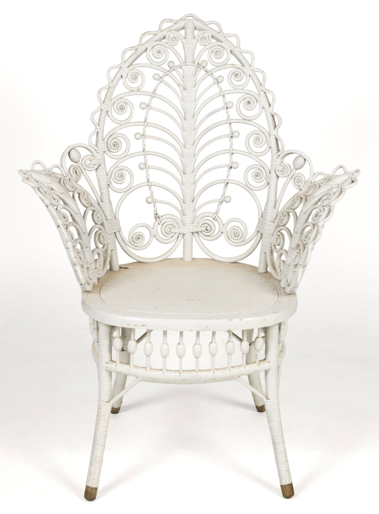 AMERICAN VICTORIAN WICKER ARMCHAIR: AMERICAN VICTORIAN WICKER ARMCHAIR, featuring a leaf-like back with flared arms over a shaped seat, the whole supported by splayed legs with brass cuff feet. Retains an old painted surface. Late