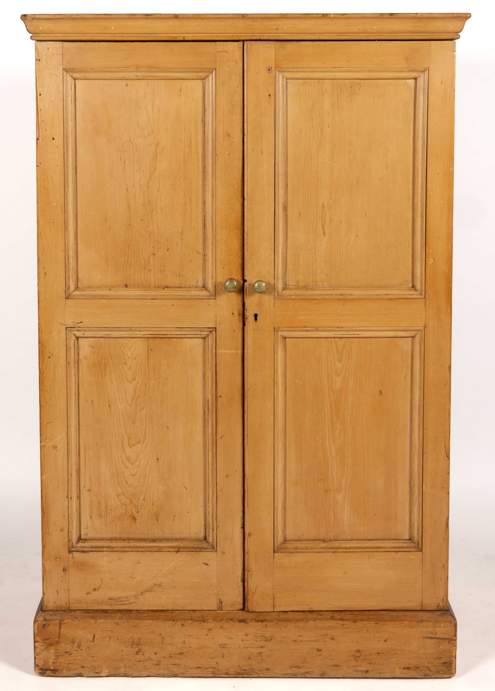 ENGLISH / BRITISH REGIONAL PINE STORAGE CUPBOARD: ENGLISH / BRITISH REGIONAL PINE STORAGE CUPBOARD, dovetailed case, the overhanging molded cornice over two hinged cabinet doors each with two fielded panels which conceal six shelves with a central