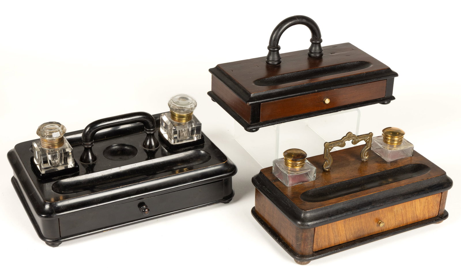 ASSORTED BRITISH WOODEN INKSTANDS, LOT OF THREE: ASSORTED BRITISH WOODEN INKSTANDS, LOT OF THREE, each of rectangular-form with a central handle, and having a single drawer to the front; comprising of an ebonized example with two colorless cut-glass
