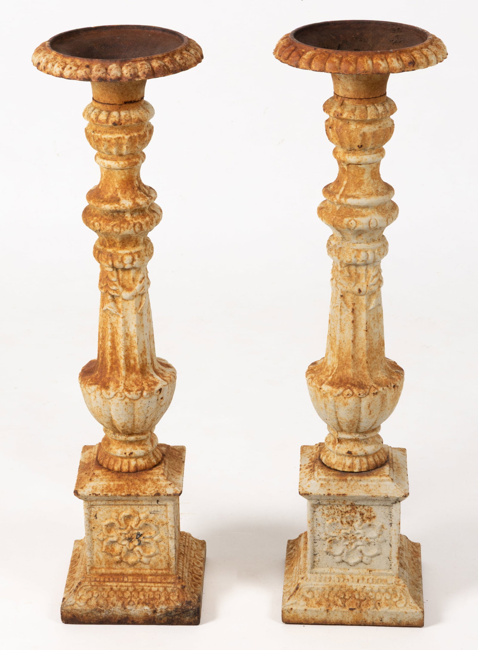 PAIR OF PAINTED CAST-IRON GARDEN CANDLESTICKS / TORCHERES: PAIR OF PAINTED CAST-IRON GARDEN CANDLESTICKS / TORCHERES, featuring an urn-form candle cup over a baluster-form stem raised on square plinth bases. Both retain their likely original white-painted sur