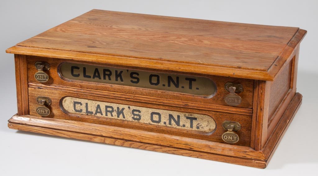 CLARK'S ONT OAK SPOOL CABINET: CLARK'S ONT OAK SPOOL CABINET, two drawers with reverse-painted glass insets, original brass pulls. Late 19th/early 20th century. 7 1/2" H, 15 1/2" x 21 1/2". Provenance: The estate collection of Rich