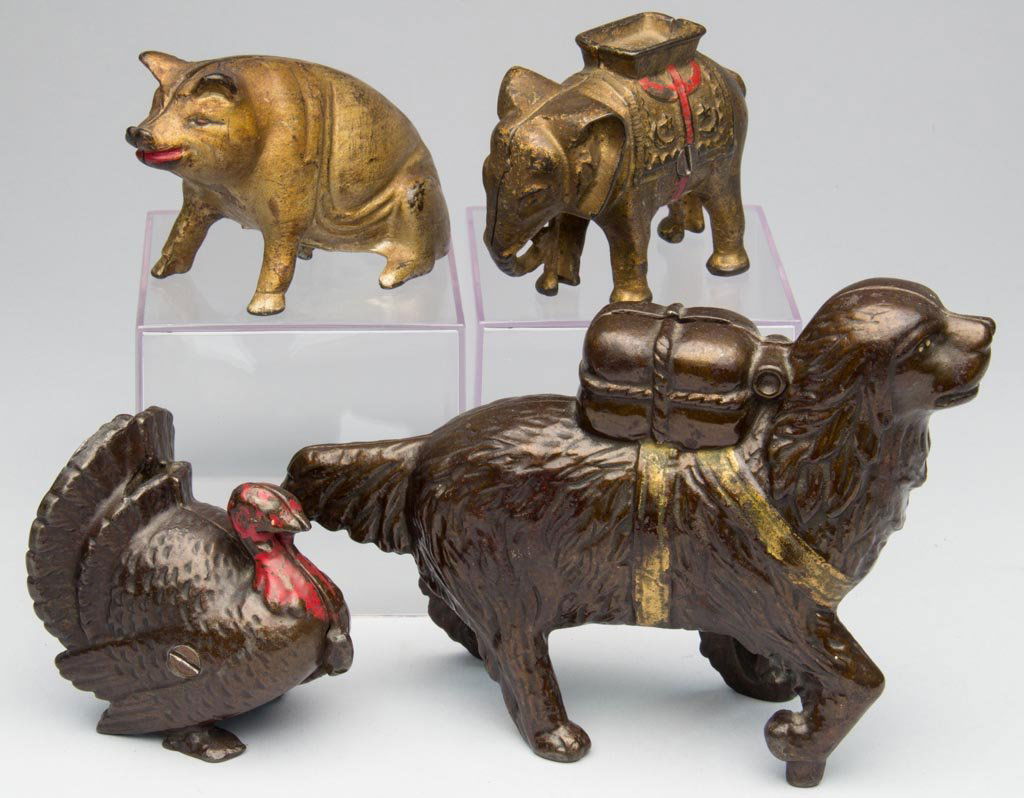 ASSORTED FIGURAL CAST-IRON PENNY BANKS, LOT OF FOUR: ASSORTED FIGURAL CAST-IRON PENNY BANKS, LOT OF FOUR, including a St. Bernard with Pack and Seated Pig. First quarter 20th century. 3 1/4" to 5 1/2" HOA. Provenance: From the collection of the late Bet