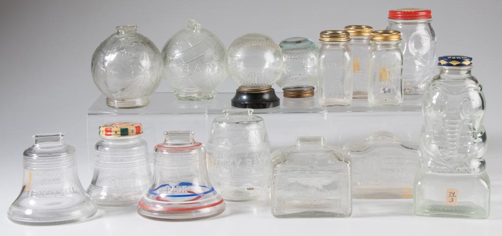 ASSORTED FIGURAL GLASS PENNY BANKS, LOT OF 15: ASSORTED FIGURAL GLASS PENNY BANKS, LOT OF 15, colorless, including a "Radio Bank" and two baseballs. 20th century. 3" to 7" H. Provenance: From the collection of the late Betty Jane Renn, Sunbury, PA