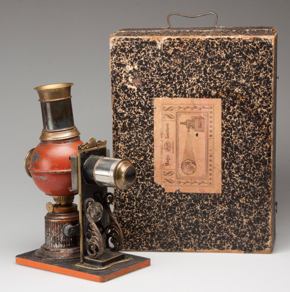 GERMAN MAGIC LANTERN: GERMAN MAGIC LANTERN, cast iron, brass and painted sheet iron, plaque lettered "E.P.", mounted on original wooden base and in original hinged, paper-covered wooden case with labels, no slides. Fourth