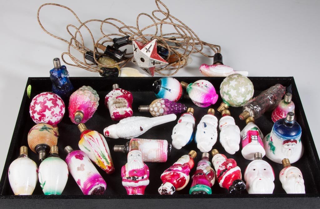 ASSORTED FIGURAL GLASS CHRISTMAS ELECTRIC BULBS: ASSORTED FIGURAL GLASS CHRISTMAS ELECTRIC BULBS, 28 loose bulbs and a strand of six bulbs, including seven Santa Clauses. First half 20th century. 2" to 4" H. Provenance: The estate collection of Rich