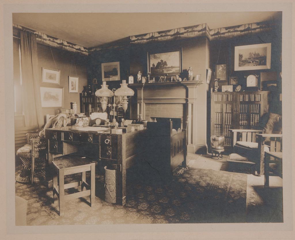AMERICAN ARTS & CRAFTS INTERIOR PHOTOGRAPH: AMERICAN ARTS & CRAFTS INTERIOR PHOTOGRAPH, mounted on heavy cardstock, depicting a study with desk, bookcases, settee and chair, and various decorative accessories, image signed "Emile Bucher, 1908".